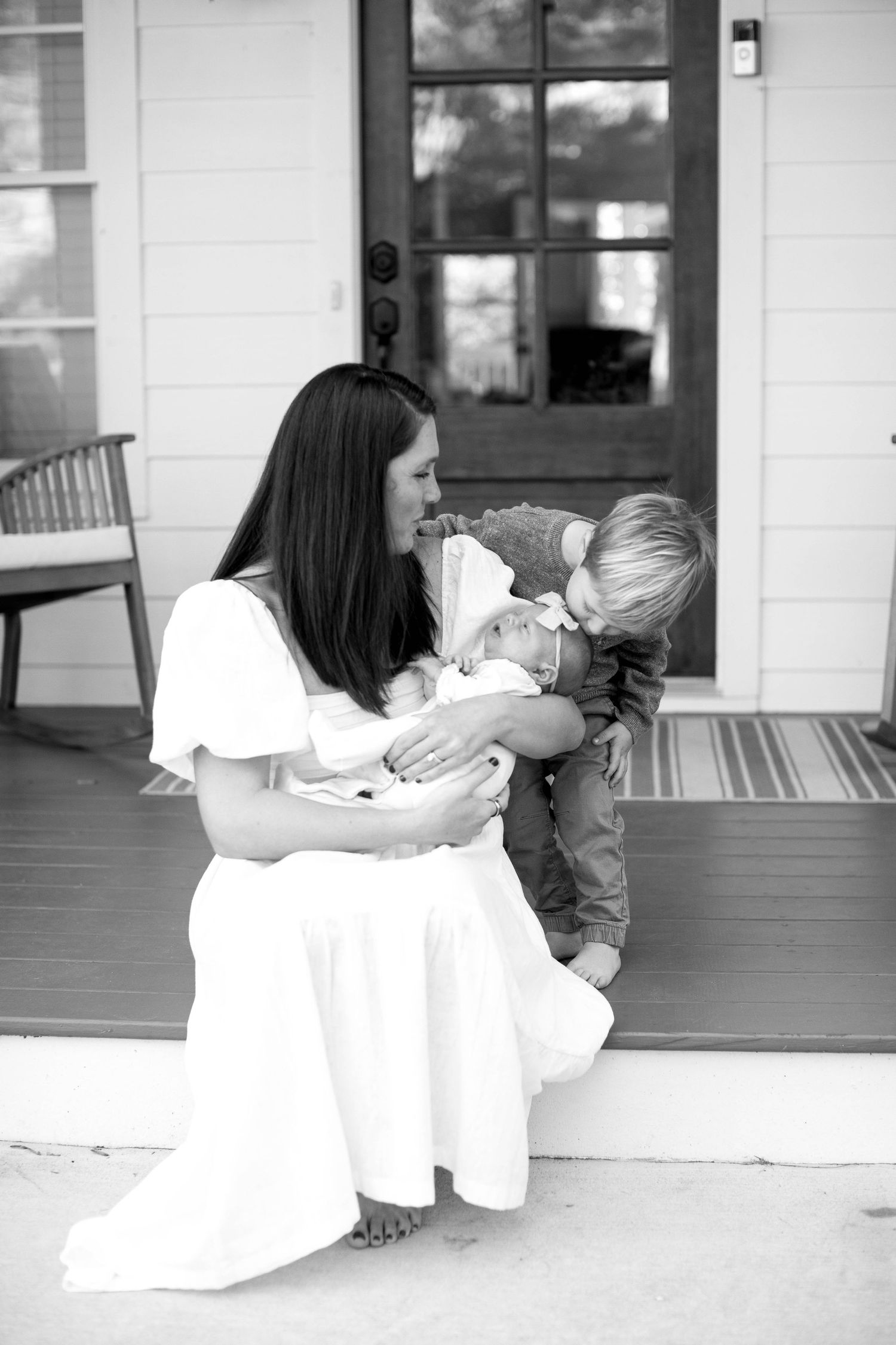 A tender moment captured on a front porch as a family bonds with their newborn.