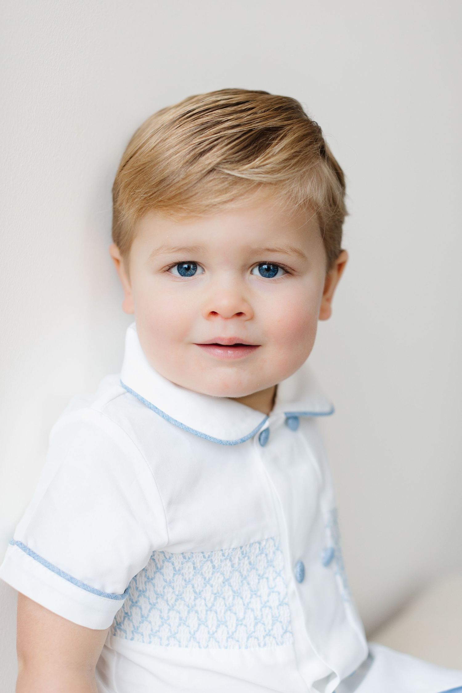 Baby wearing white collared shirt and light blue bib smiles sweetly in three close-up portrait photos.