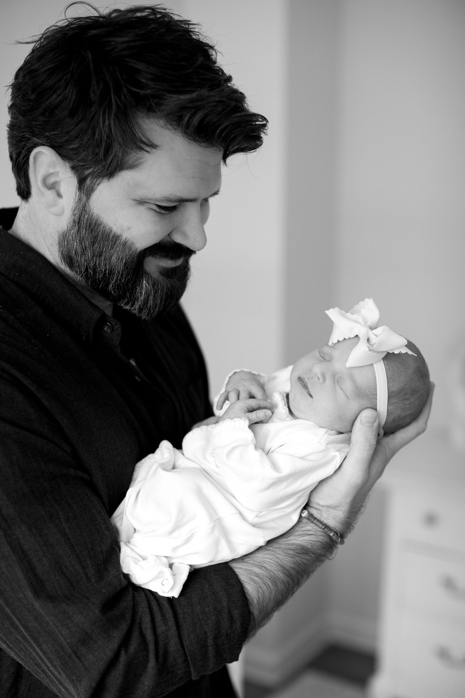 Black and white photos of parent tenderly holding and kissing newborn.