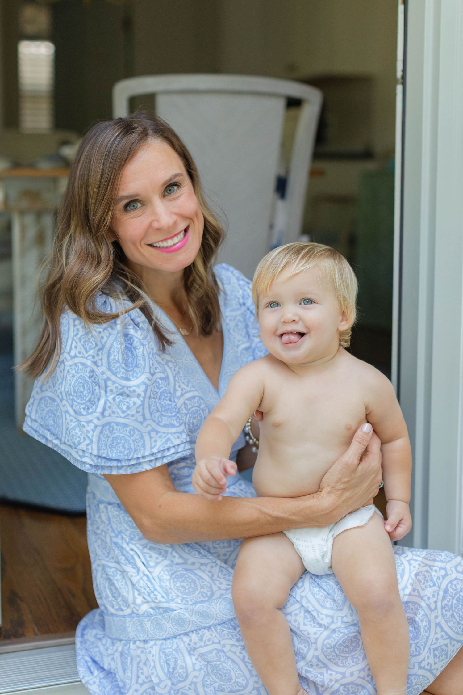 A playful outdoor photoshoot with mother and baby wearing matching blue paisley dresses.