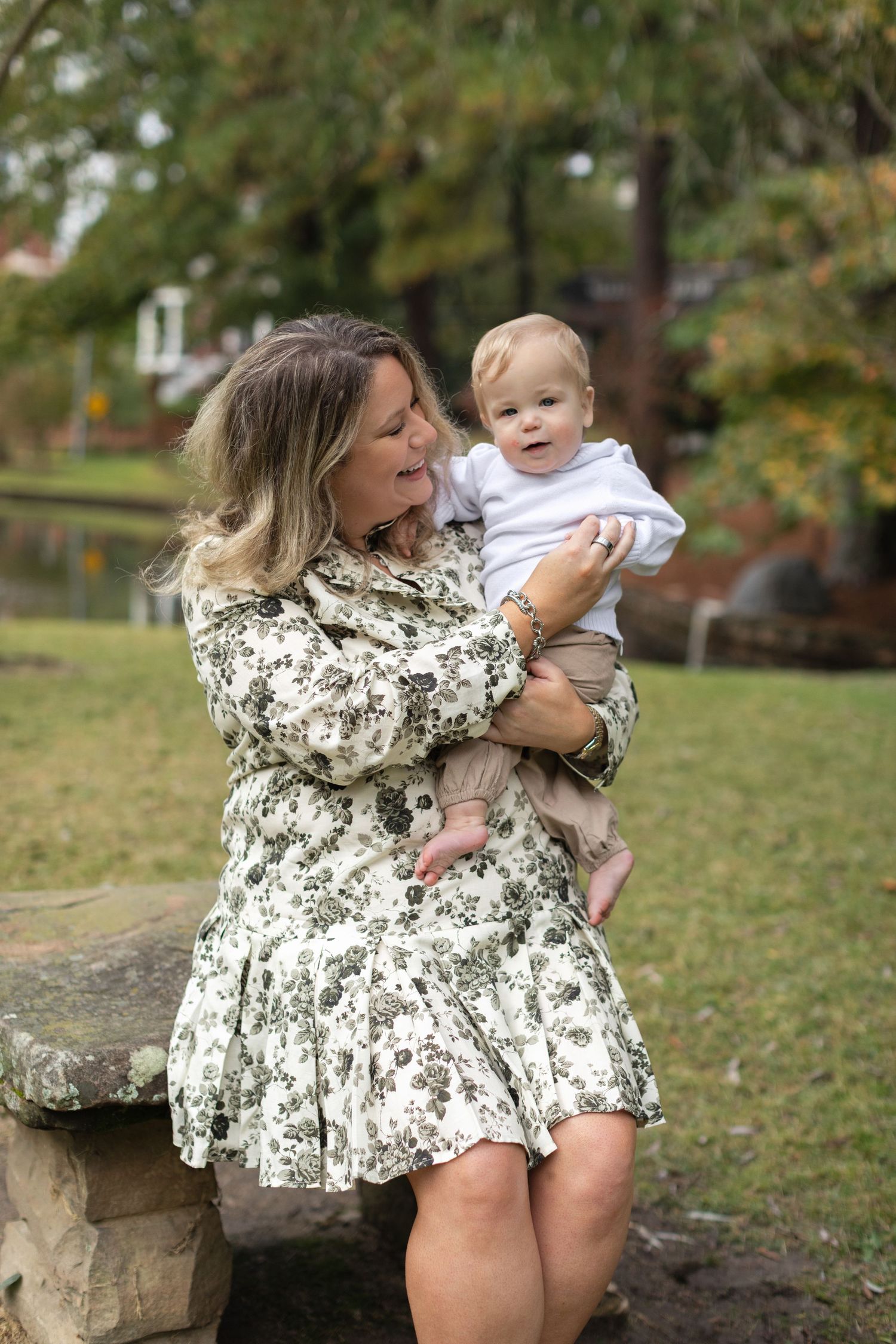 A series of candid outdoor photos showing tender moments between parent and baby on a grassy lawn with autumn trees.