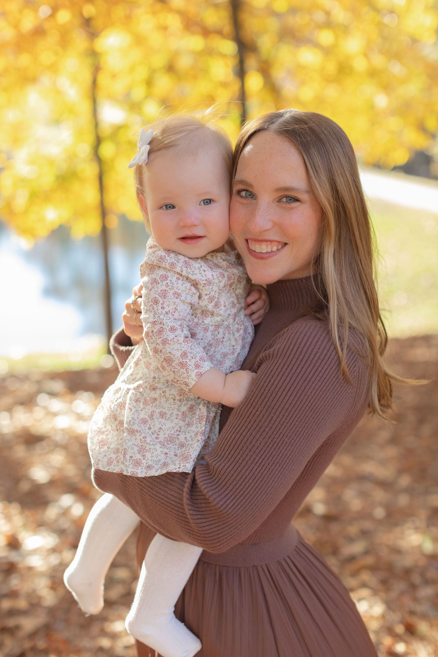Two people embrace joyfully among golden autumn leaves on a sunny fall day in the park.