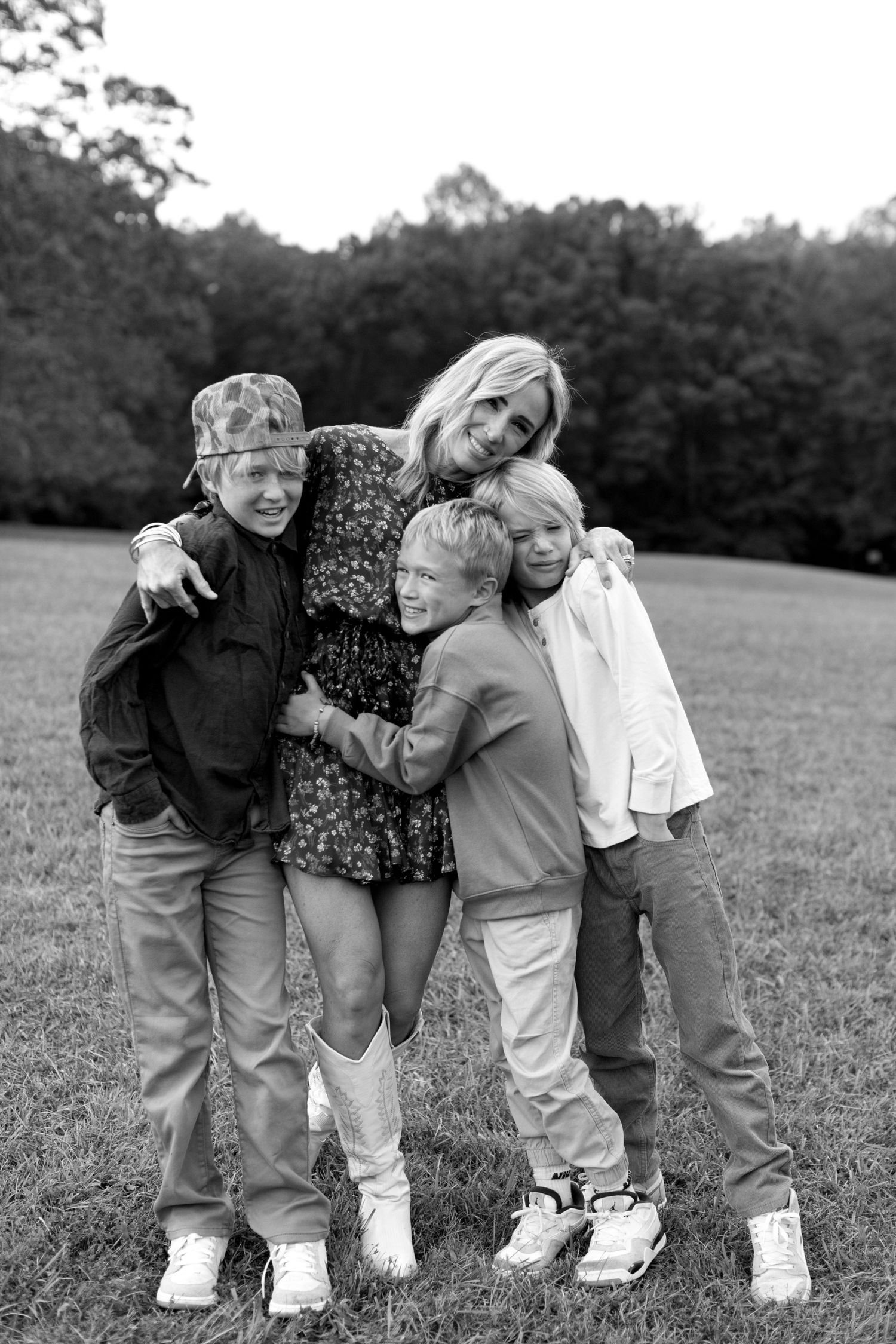 A black and white photo series showing children huddled together playfully in a grassy field.
