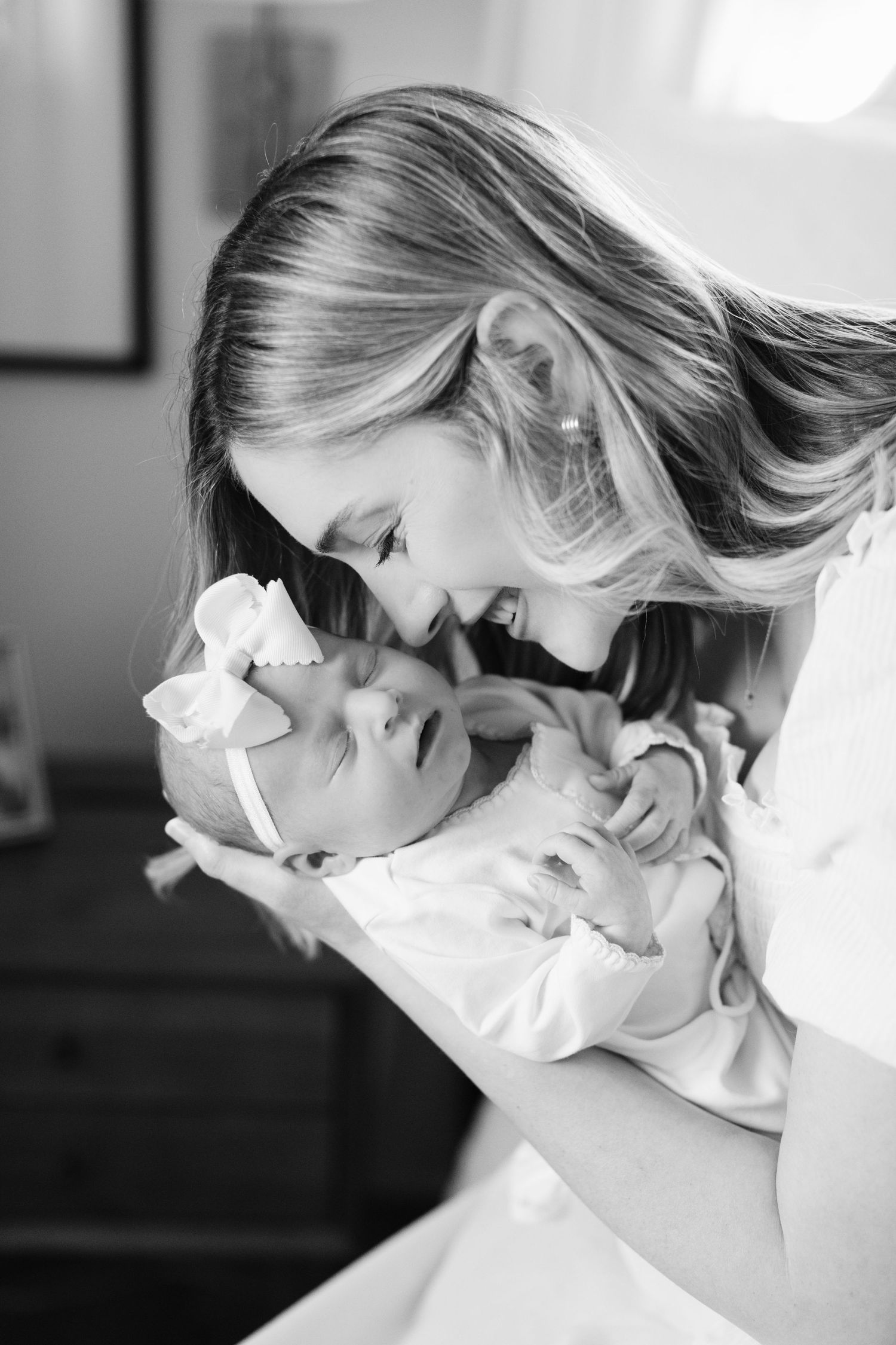 A tender black and white moment between parent and baby wearing matching white outfits.