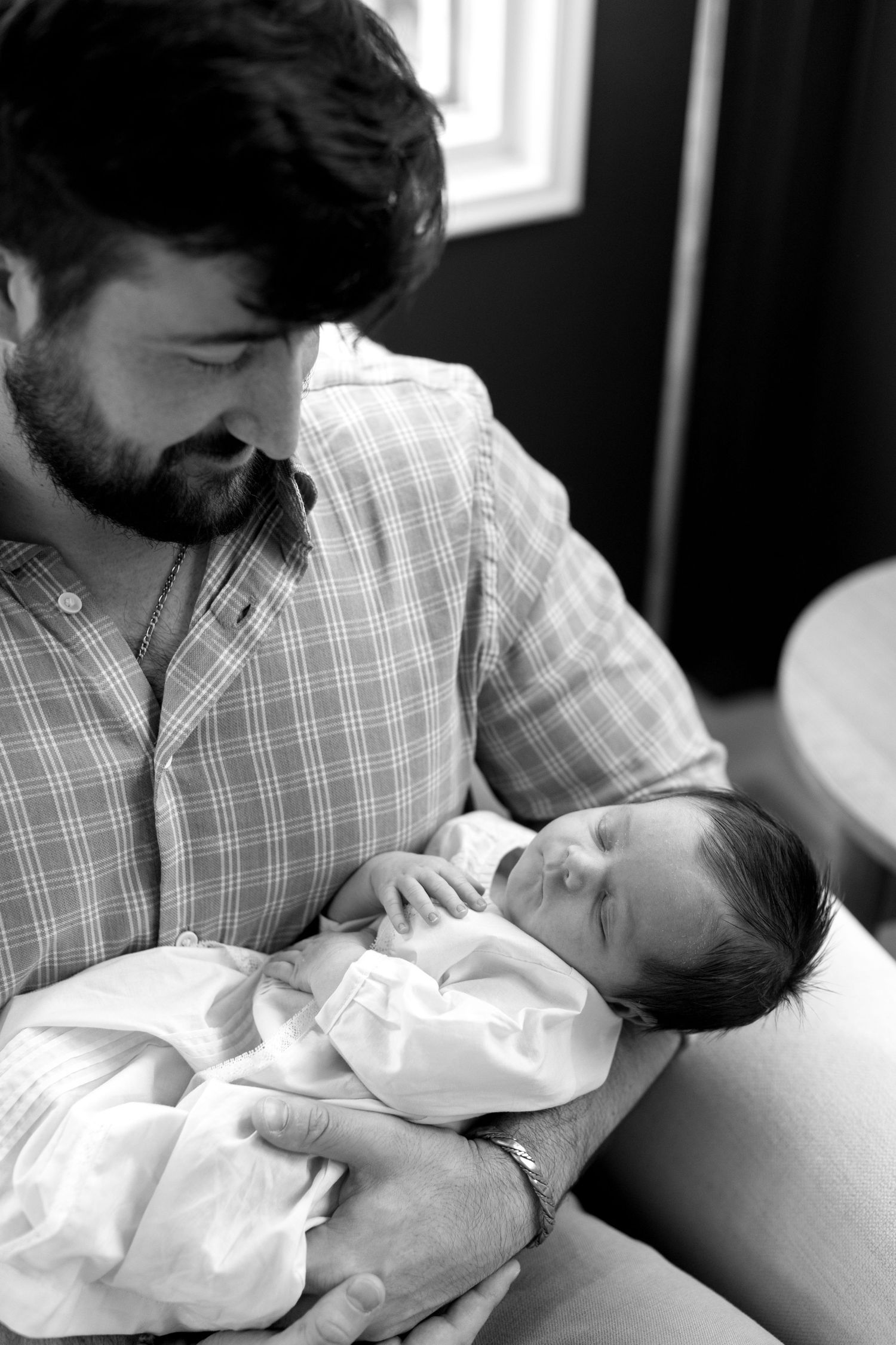Black and white series showing gentle moments between a parent and newborn.