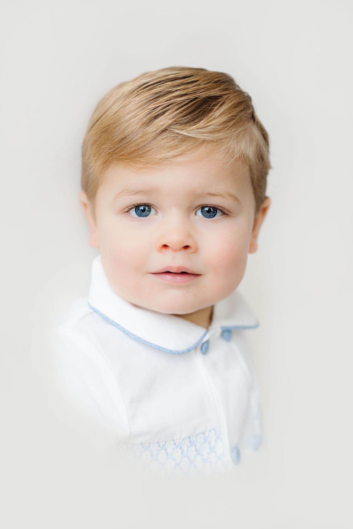 A series of four close-up photos showing a baby in white clothing against a light background.