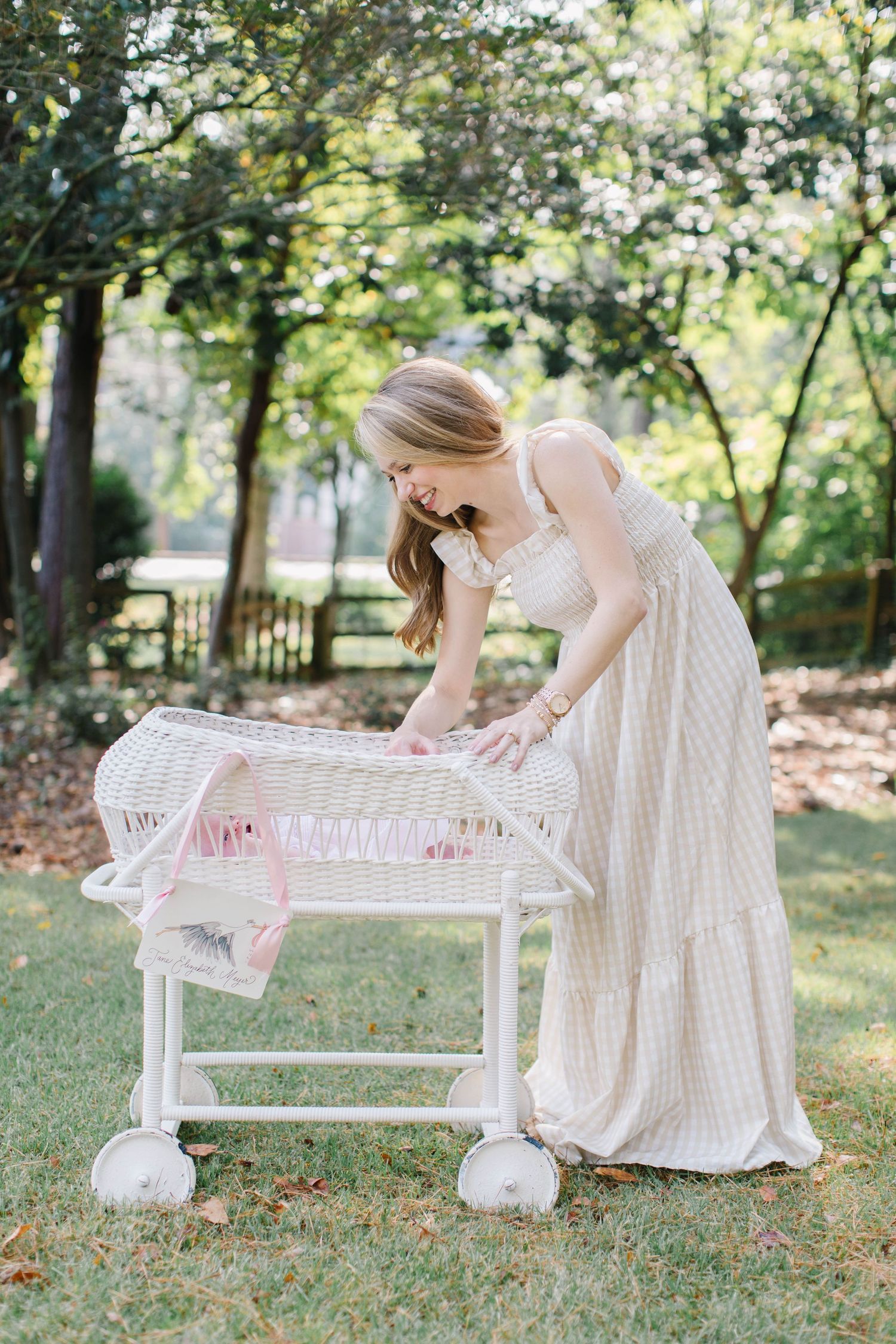 In a serene garden setting a person in a white dress reaches down to touch a decorative white bench.