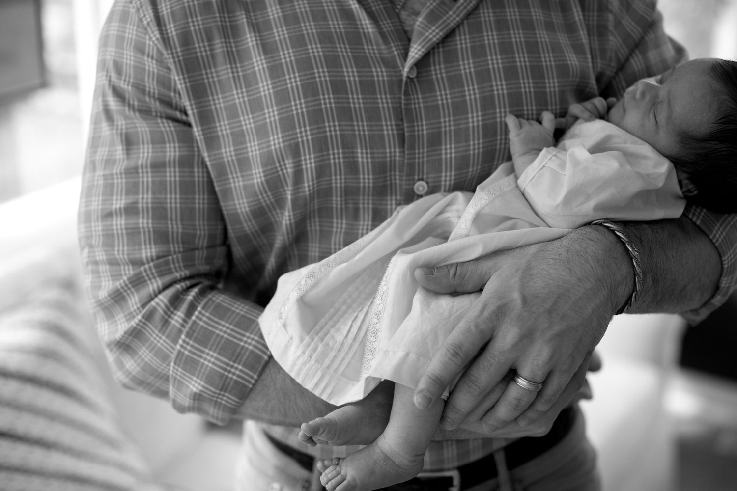 A sequence of black and white photos showing a baby being gently held and cradled in someone's arms.