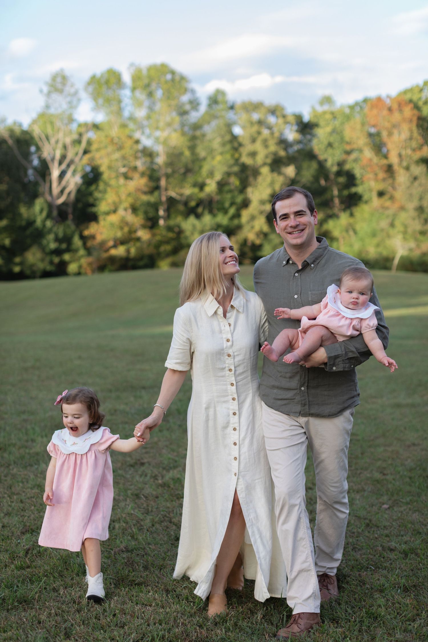 Family enjoying a playful moment together on grassy field during autumn photo session.
