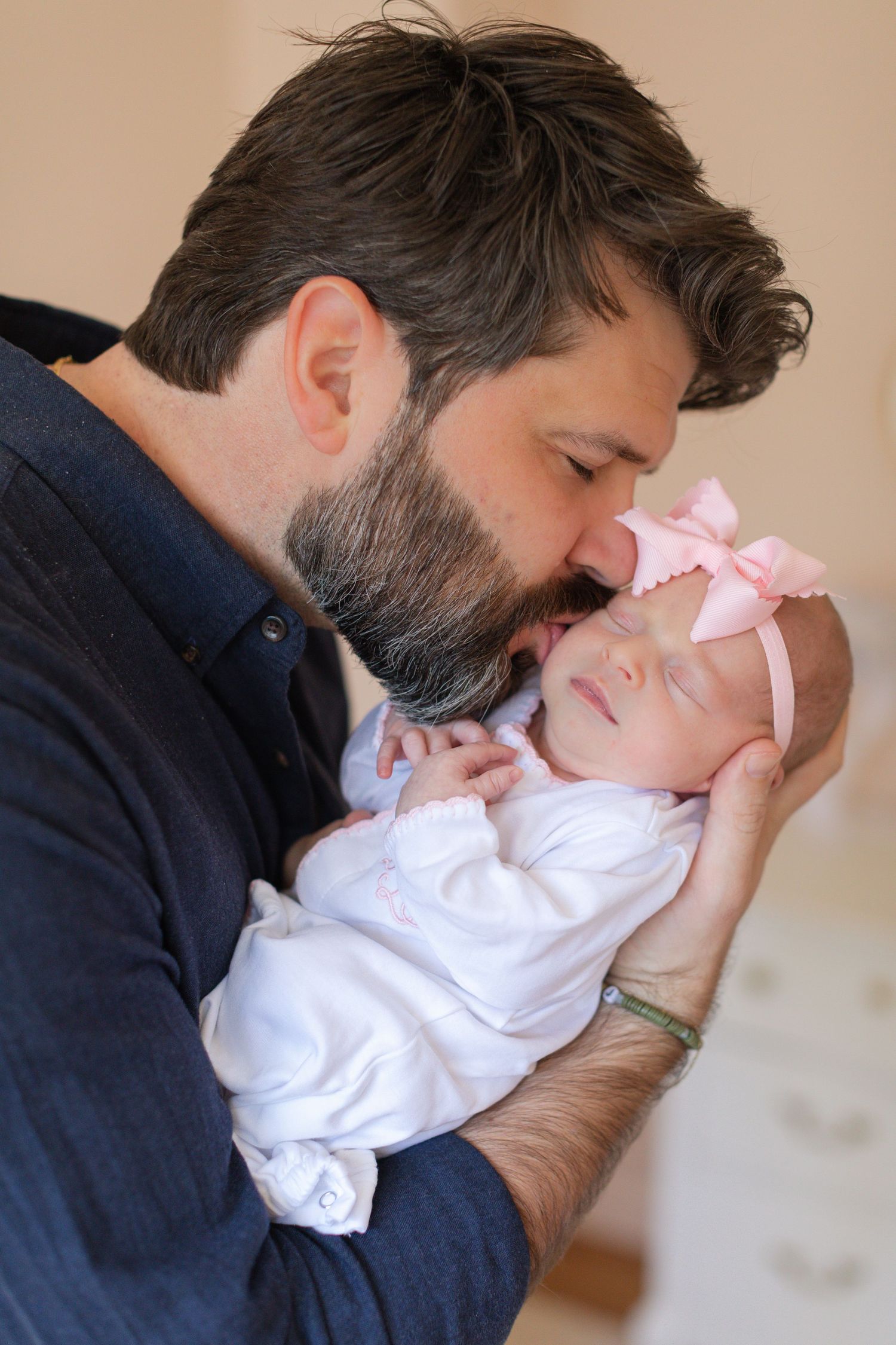 A sequence of intimate photos showing tender moments with a newborn baby wearing a pink bow and white outfit.