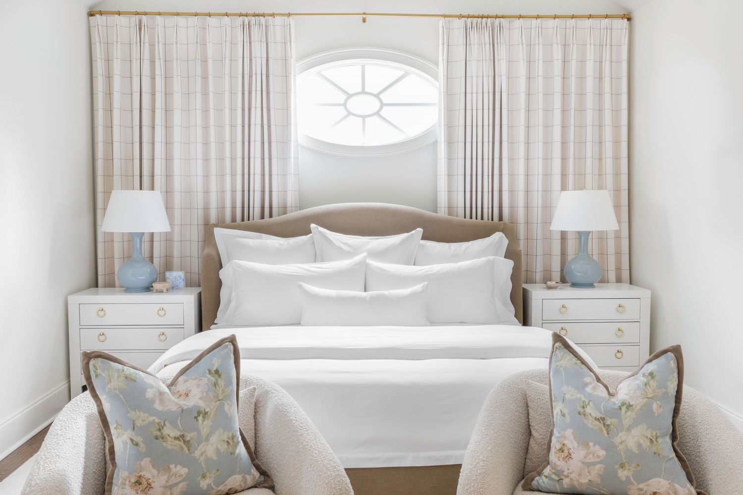 A serene coastal-themed bedroom with white bedding, soft blue accents, and natural light flowing through sheer curtains.