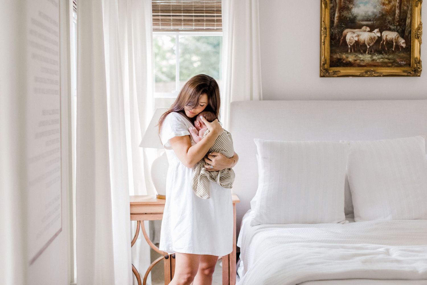A bright, airy bedroom scene with white bedding and classic artwork on the wall.