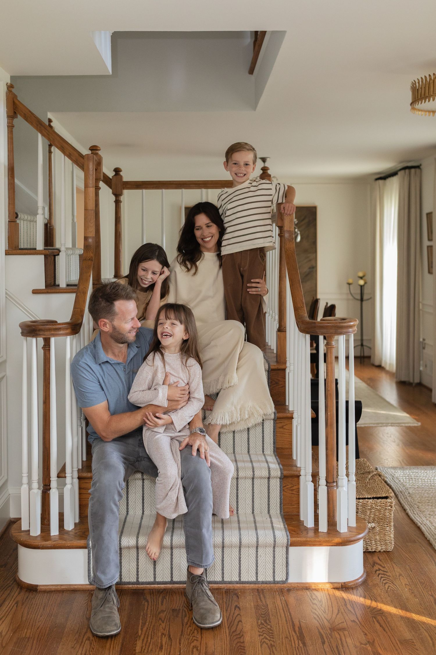 A series of candid family moments captured along a staircase in a bright home interior.