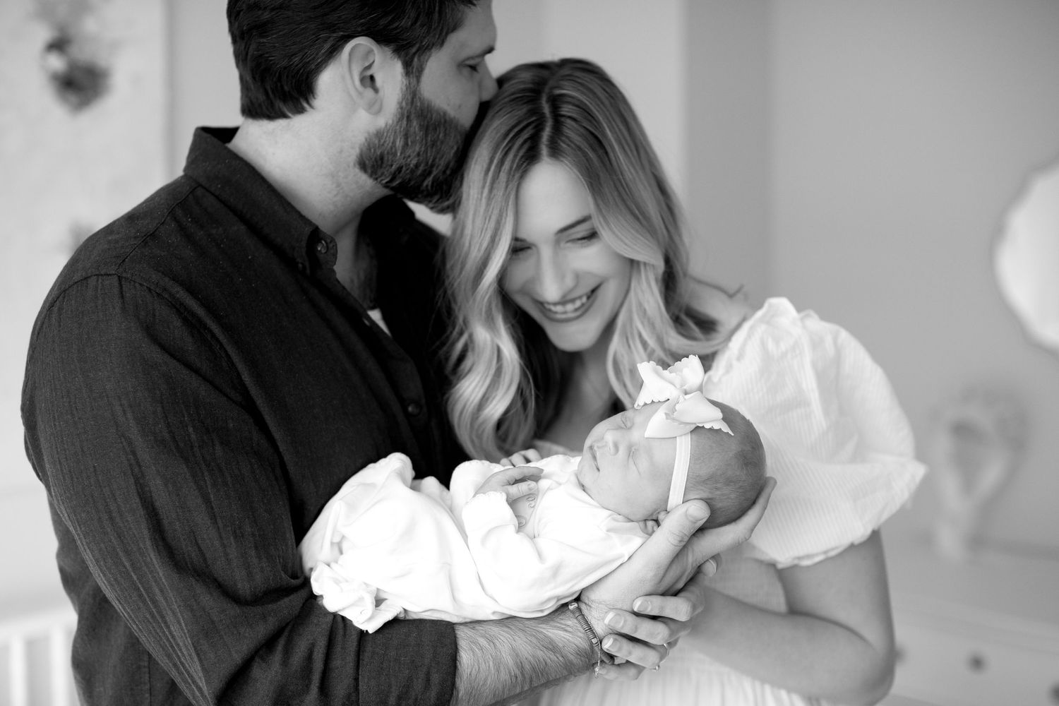 A series of black and white photos showing tender moments between parents and their newborn baby.