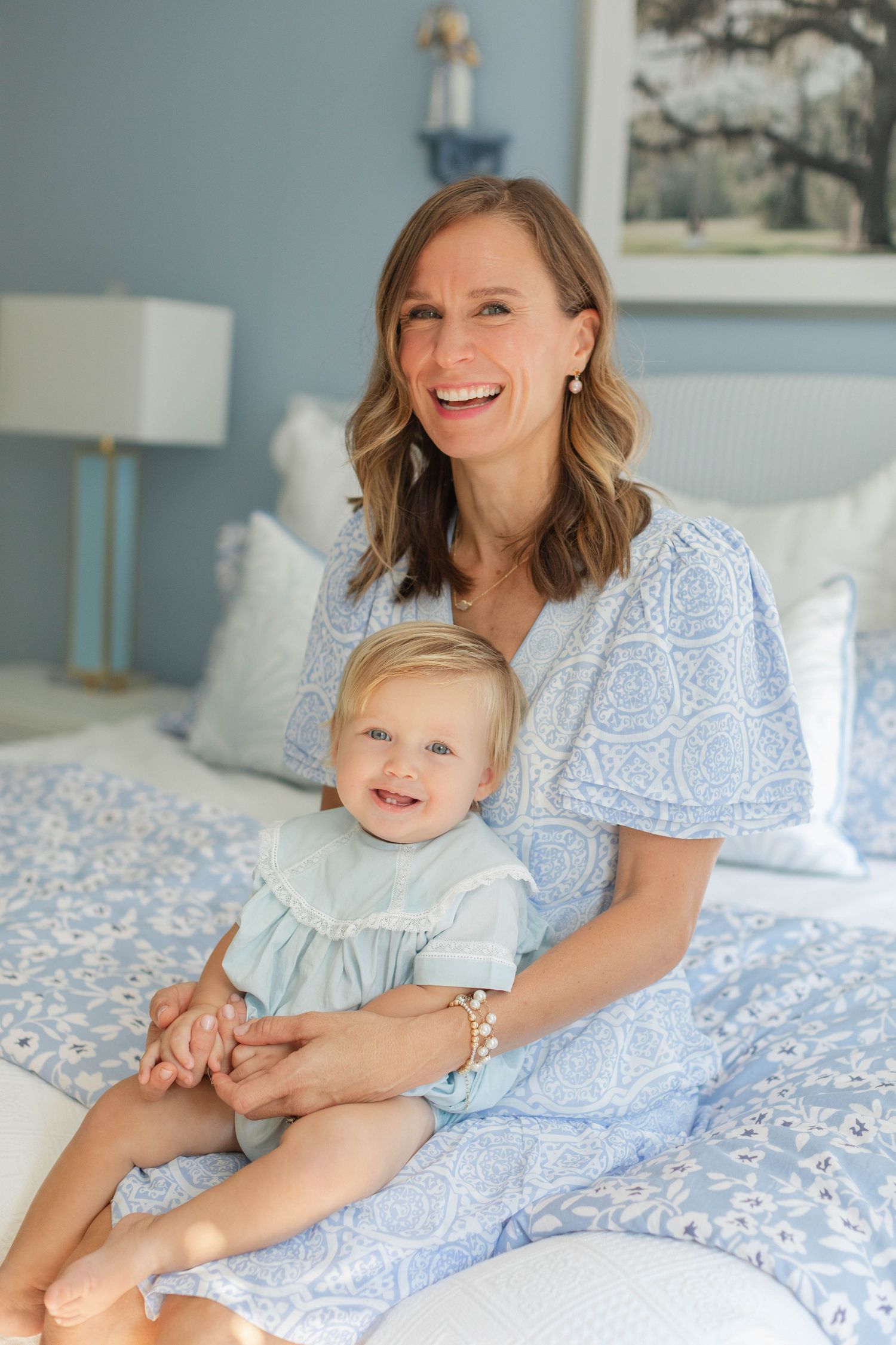 A parent and child share joyful moments while relaxing together on a blue and white patterned bedspread.