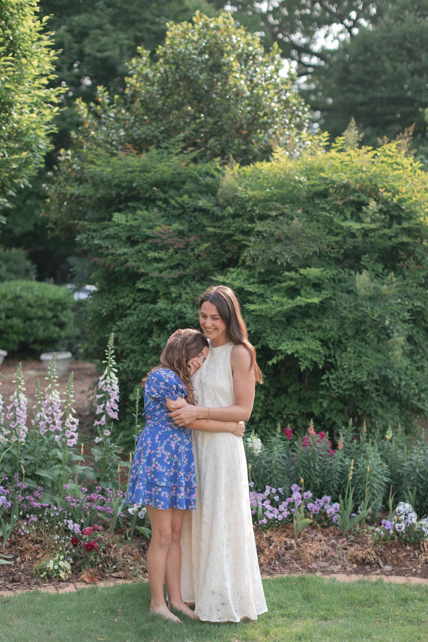 People in white and blue outfits share a playful moment in a flower-filled garden.