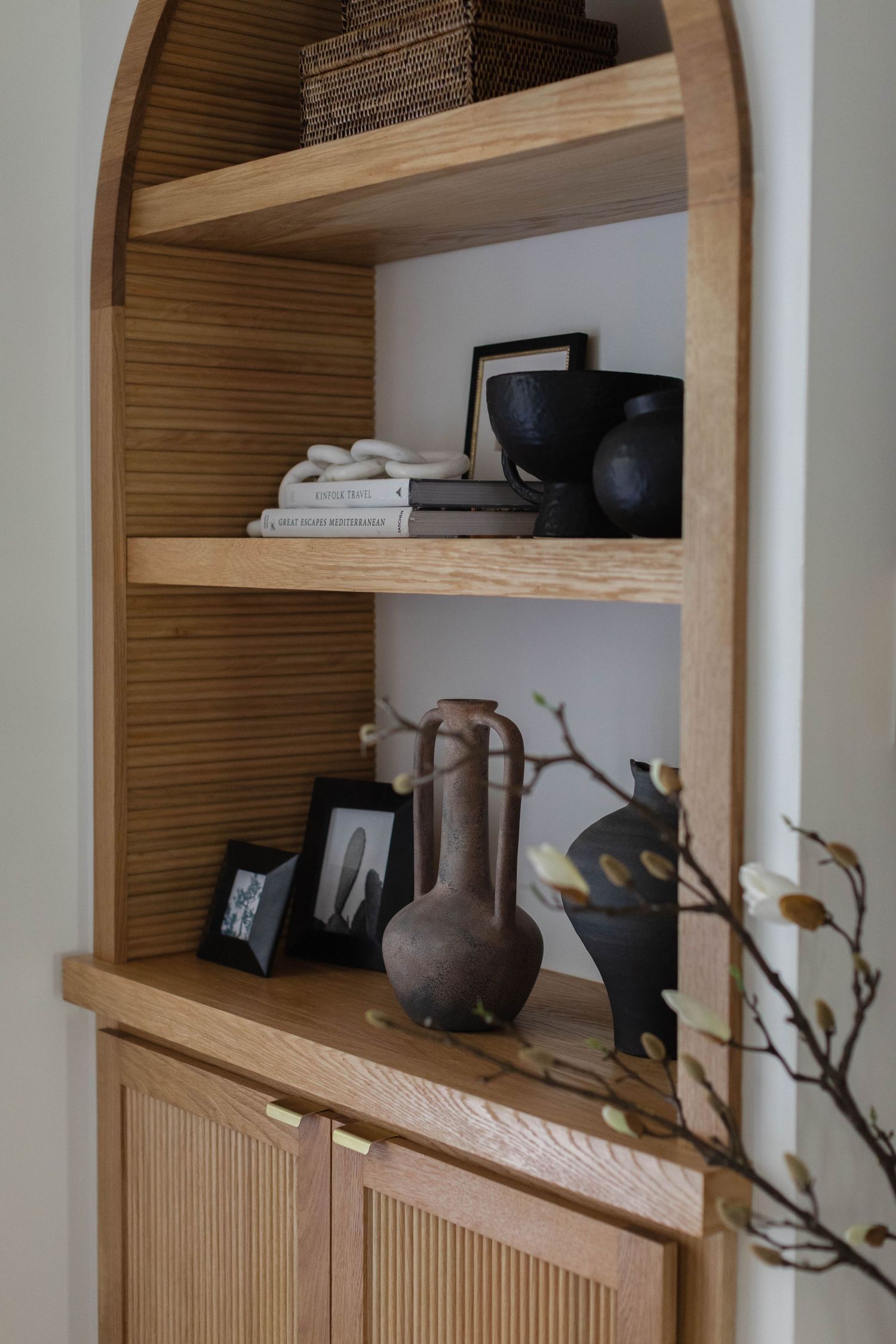 Built-in wooden shelves display artisanal pottery, towels, and decorative items in a modern minimalist style.
