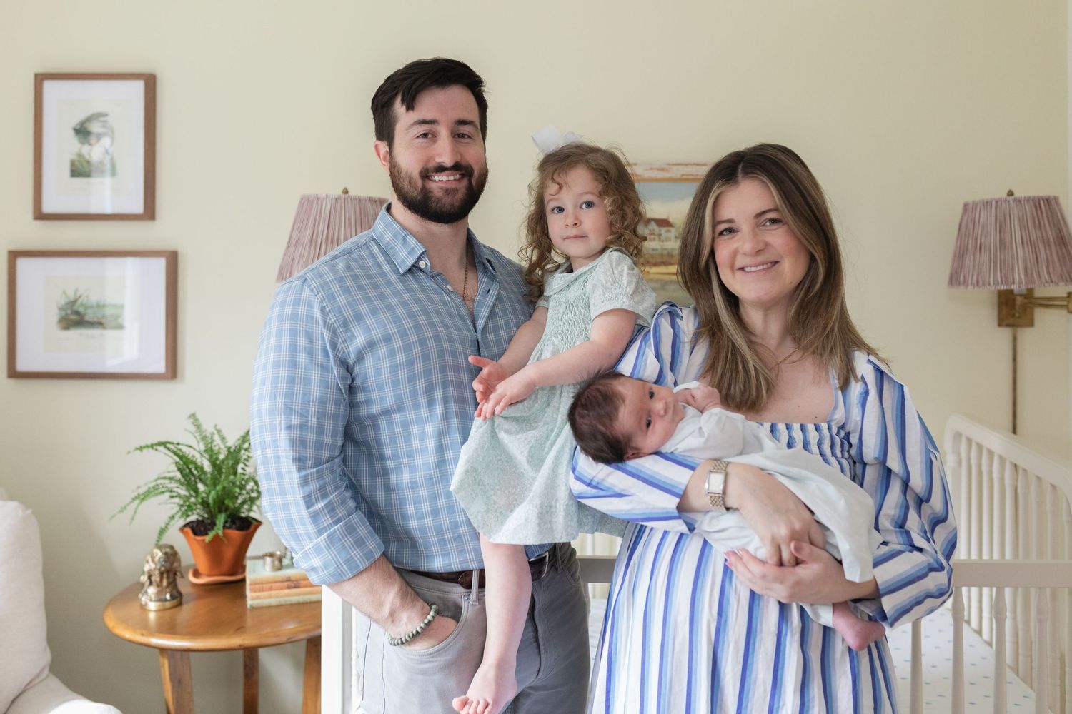 Parent in blue striped dress holding and gazing lovingly at newborn baby in peaceful nursery setting.