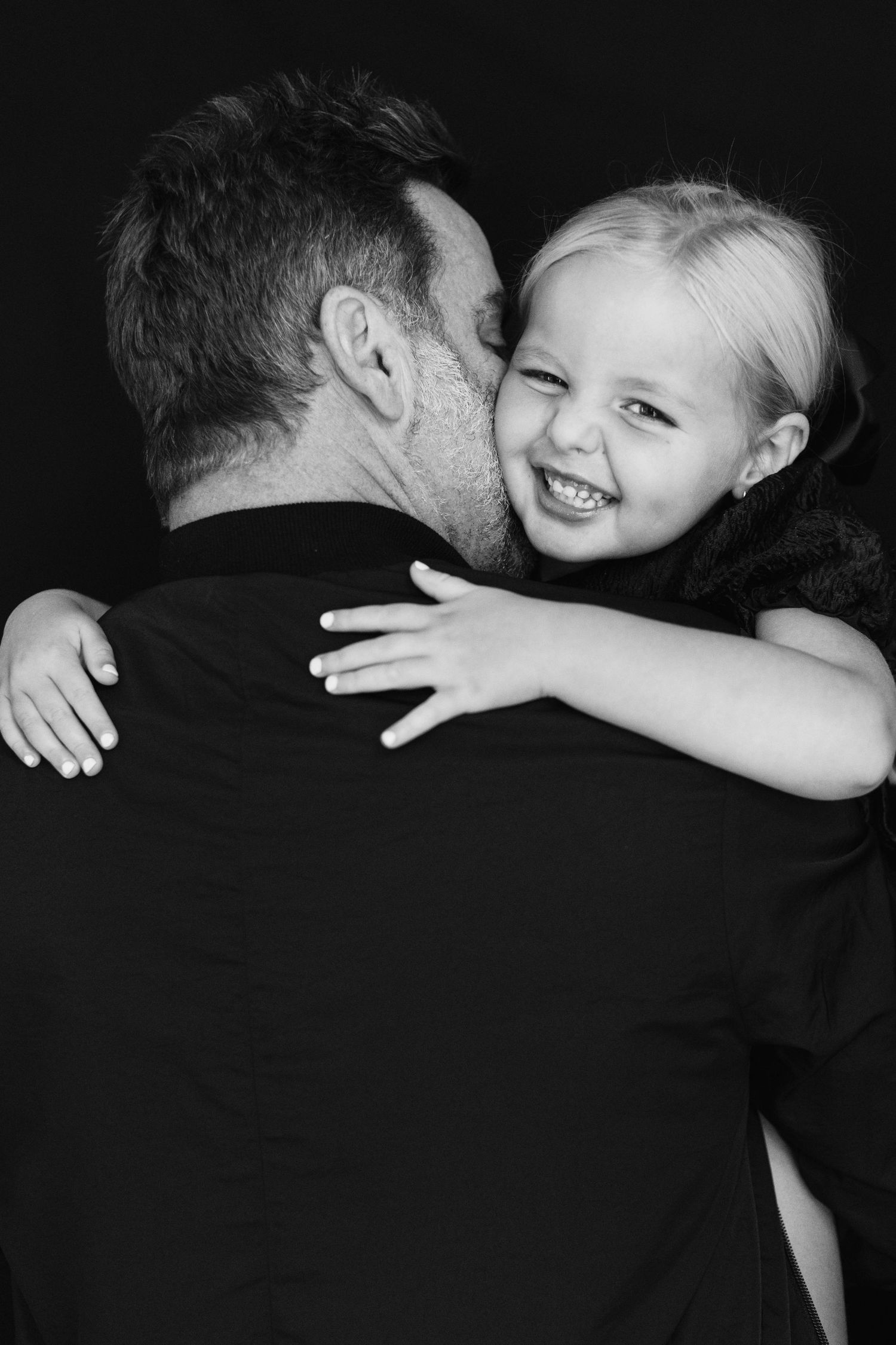 Black and white photo series showing tender hugging moments between parent and child in dramatic lighting.