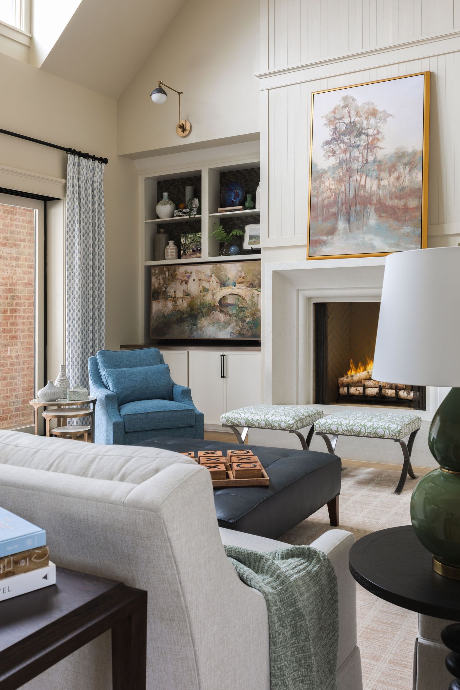 Modern living room interior with blue accent chair, white sofa, and built-in fireplace showcasing contemporary design elements.