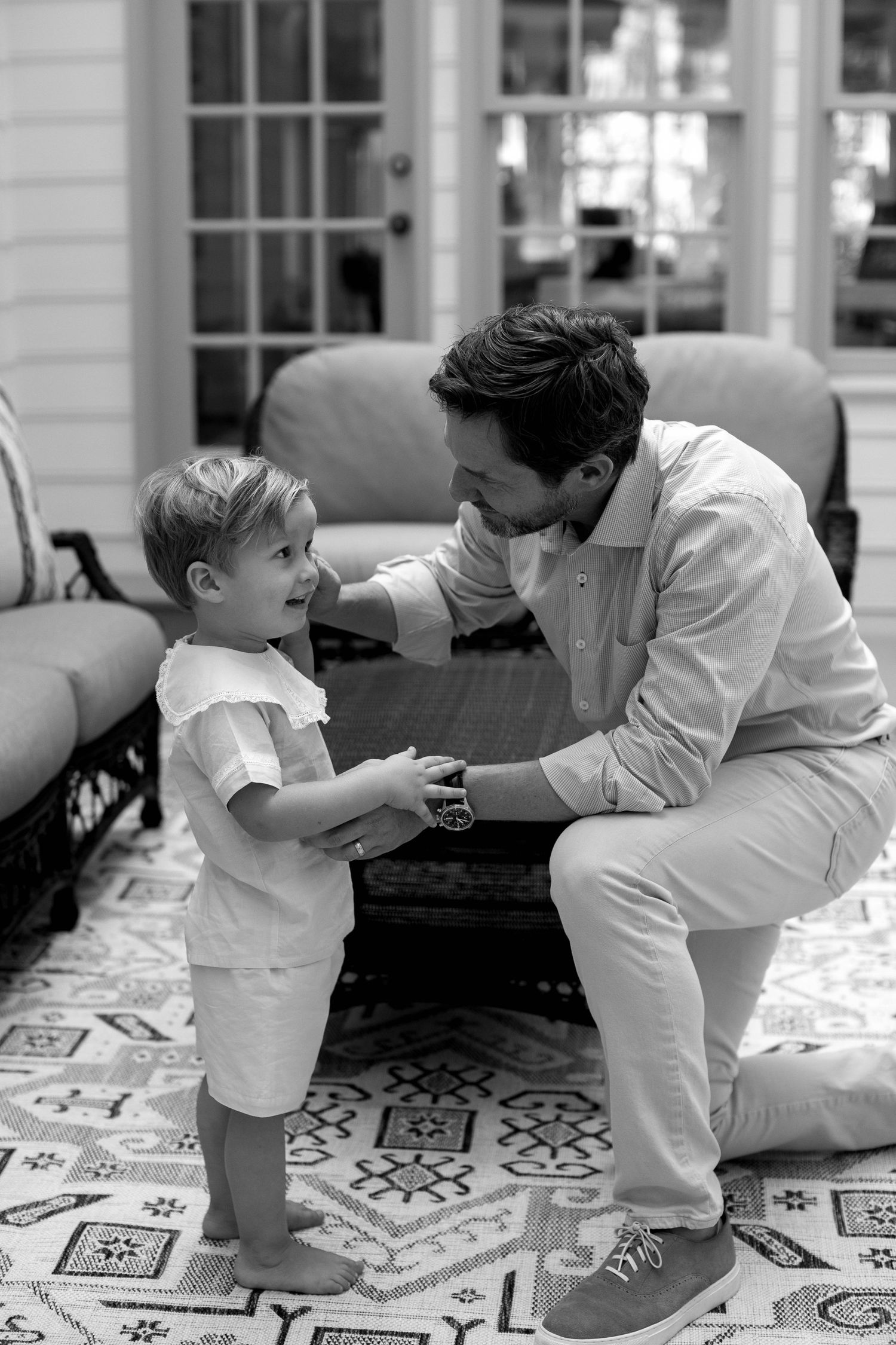 A sequence of black and white photos showing tender interactions between parent and child on a decorative floor.