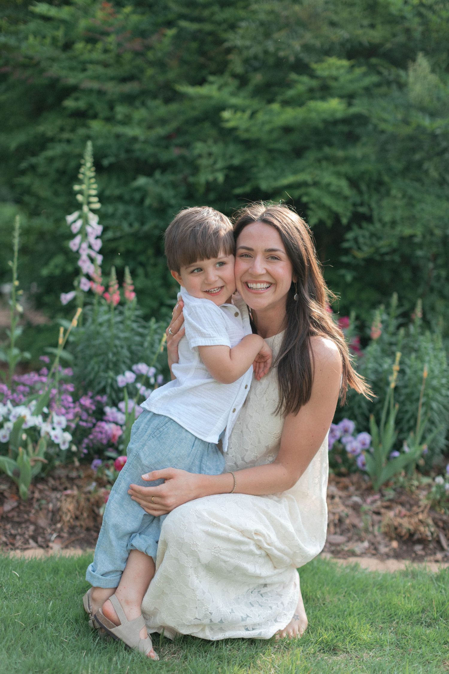 An intimate moment shared in a garden setting with flowering plants and green trees.