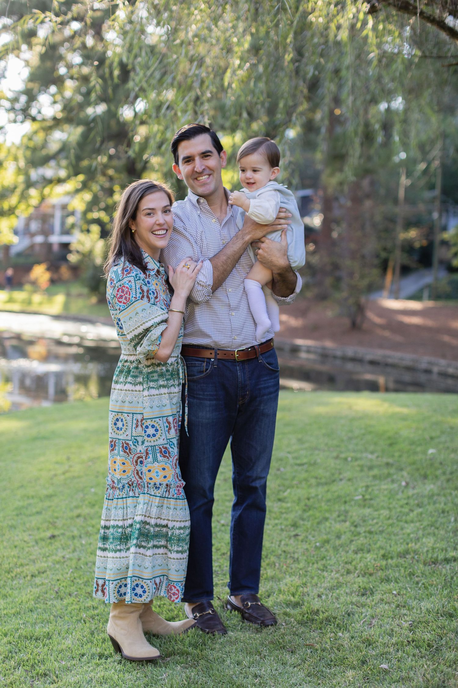 A family stands together on a grassy lawn during a sunny outdoor photo session.