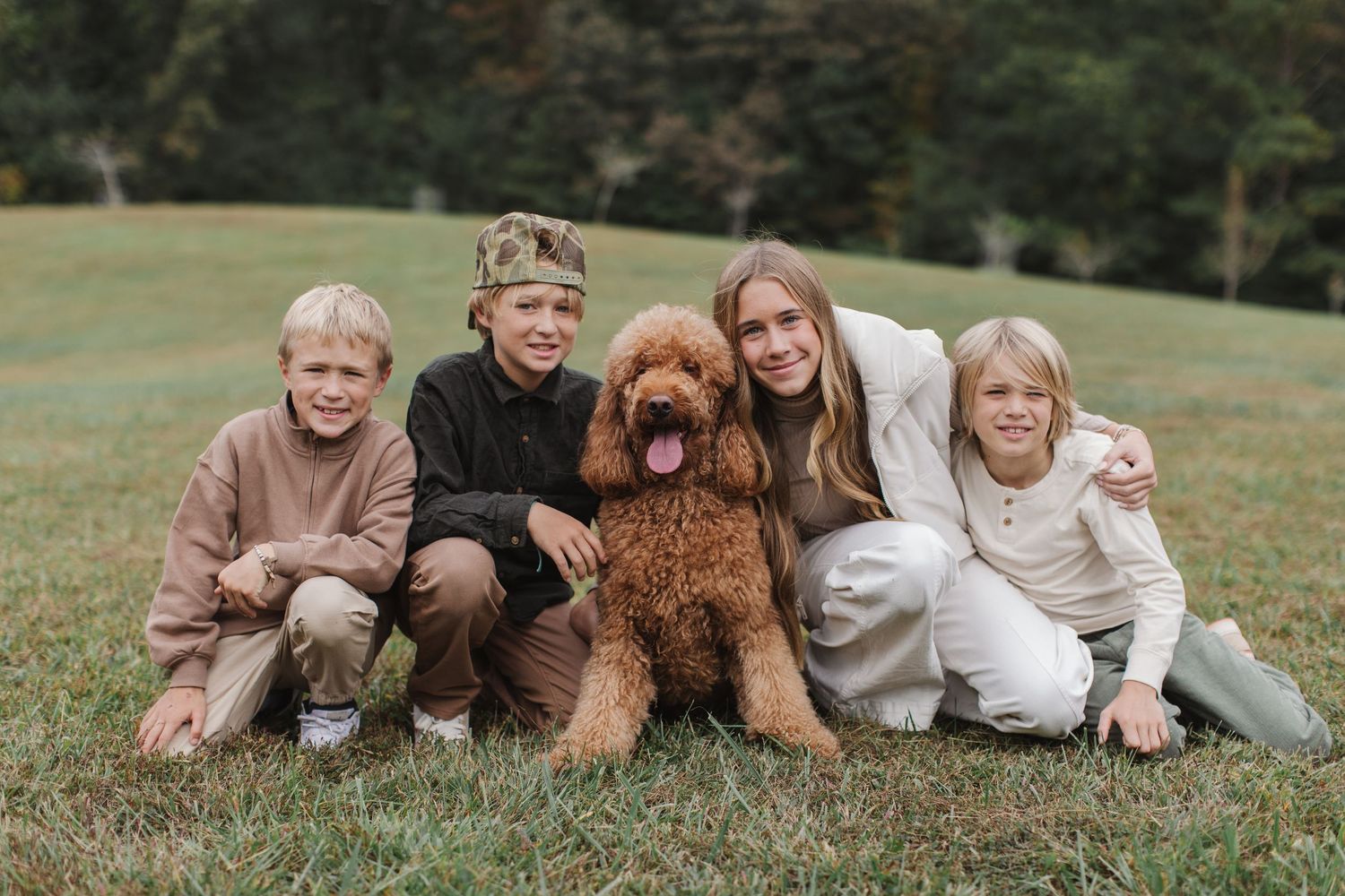 People laying in grass with their brown dog during an outdoor autumn photoshoot session.