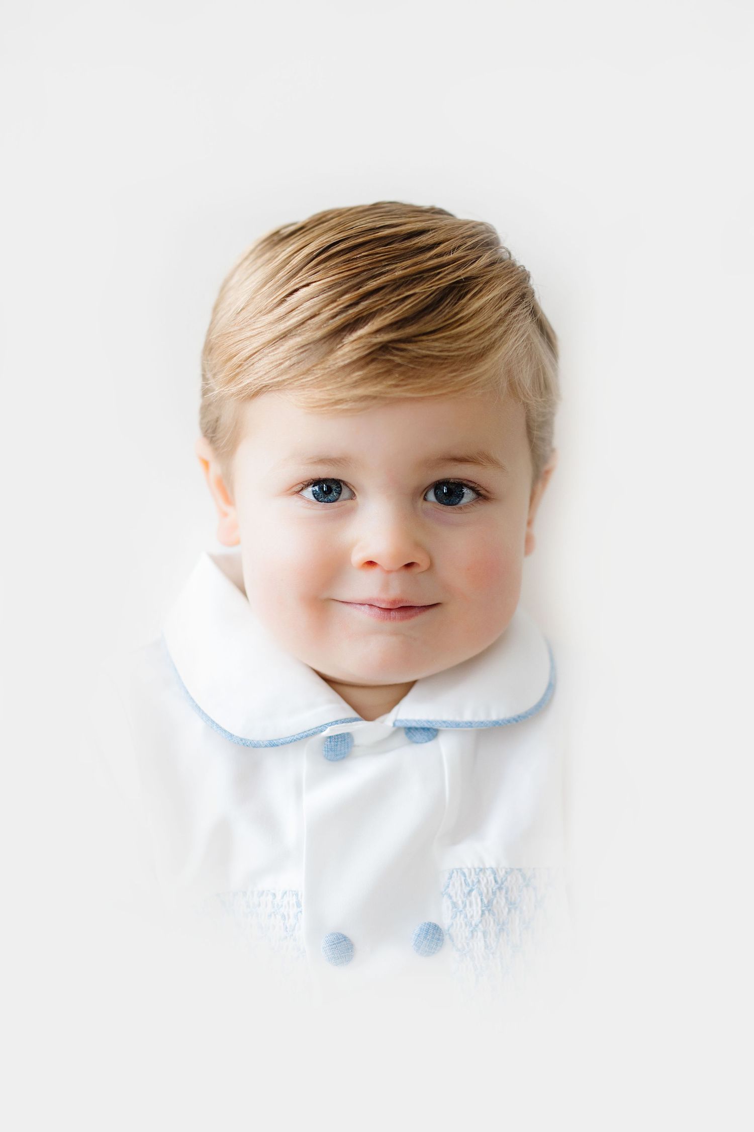 Four artistic portrait photos of a baby in white clothing against a light background, arranged in a row.