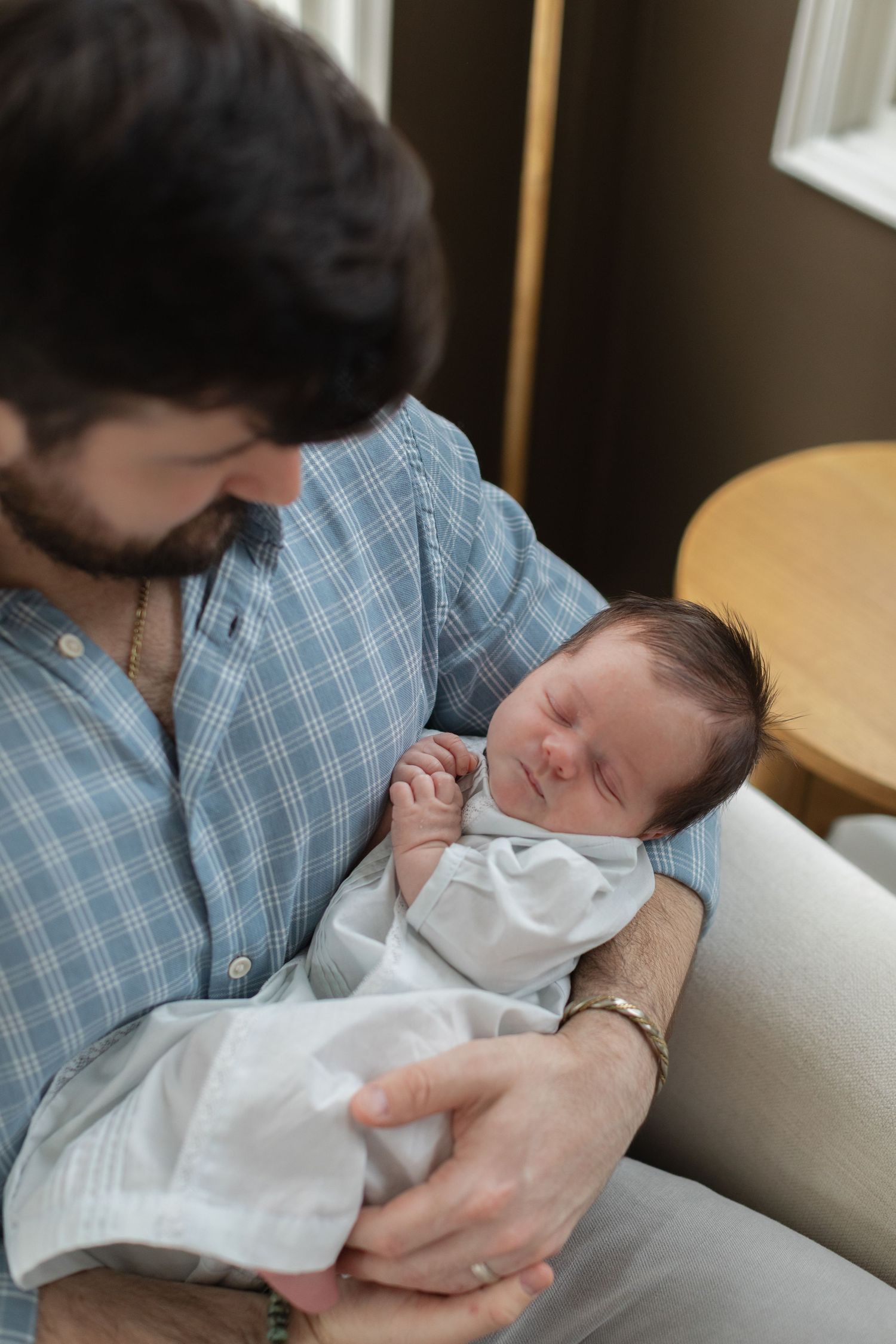 A sequence of intimate photos showing a parent cradling a sleeping newborn baby on a couch.