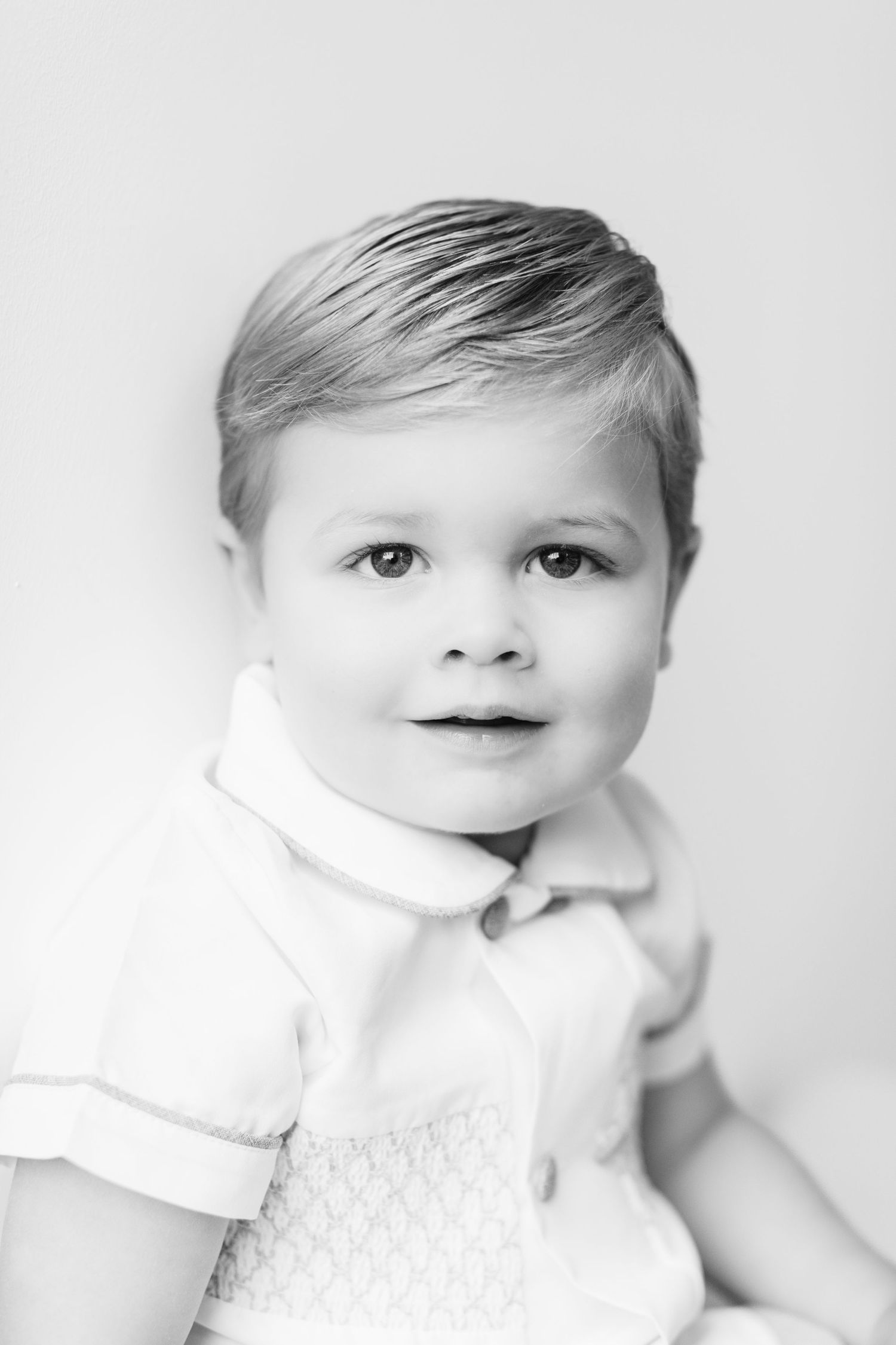 Artistic black and white close-up shots of an infant wearing white against a neutral backdrop.