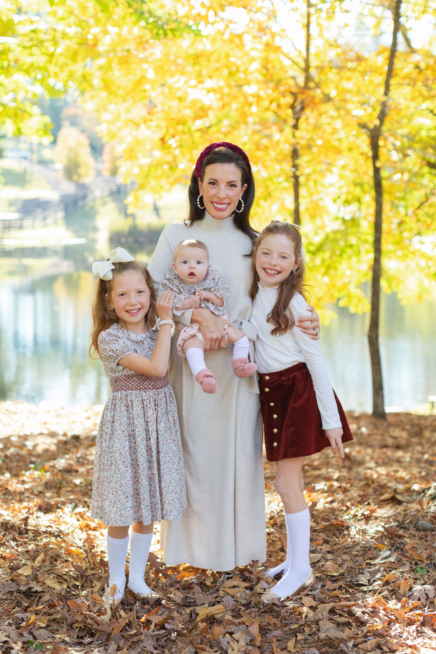 Family portrait outdoors with autumn foliage and lake backdrop showing seasonal fall colors.