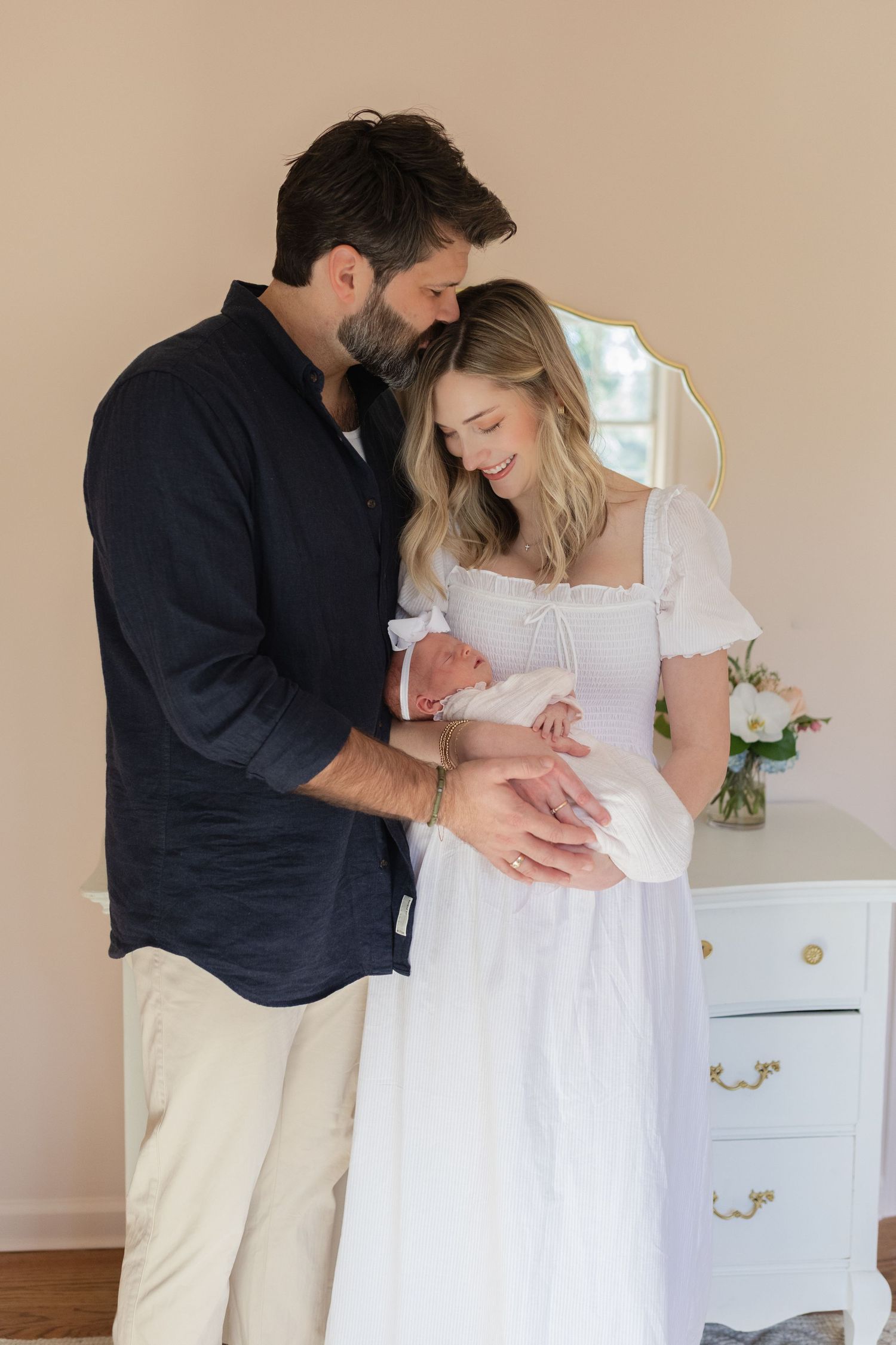 Parents in white and navy outfits share an intimate moment while embracing.