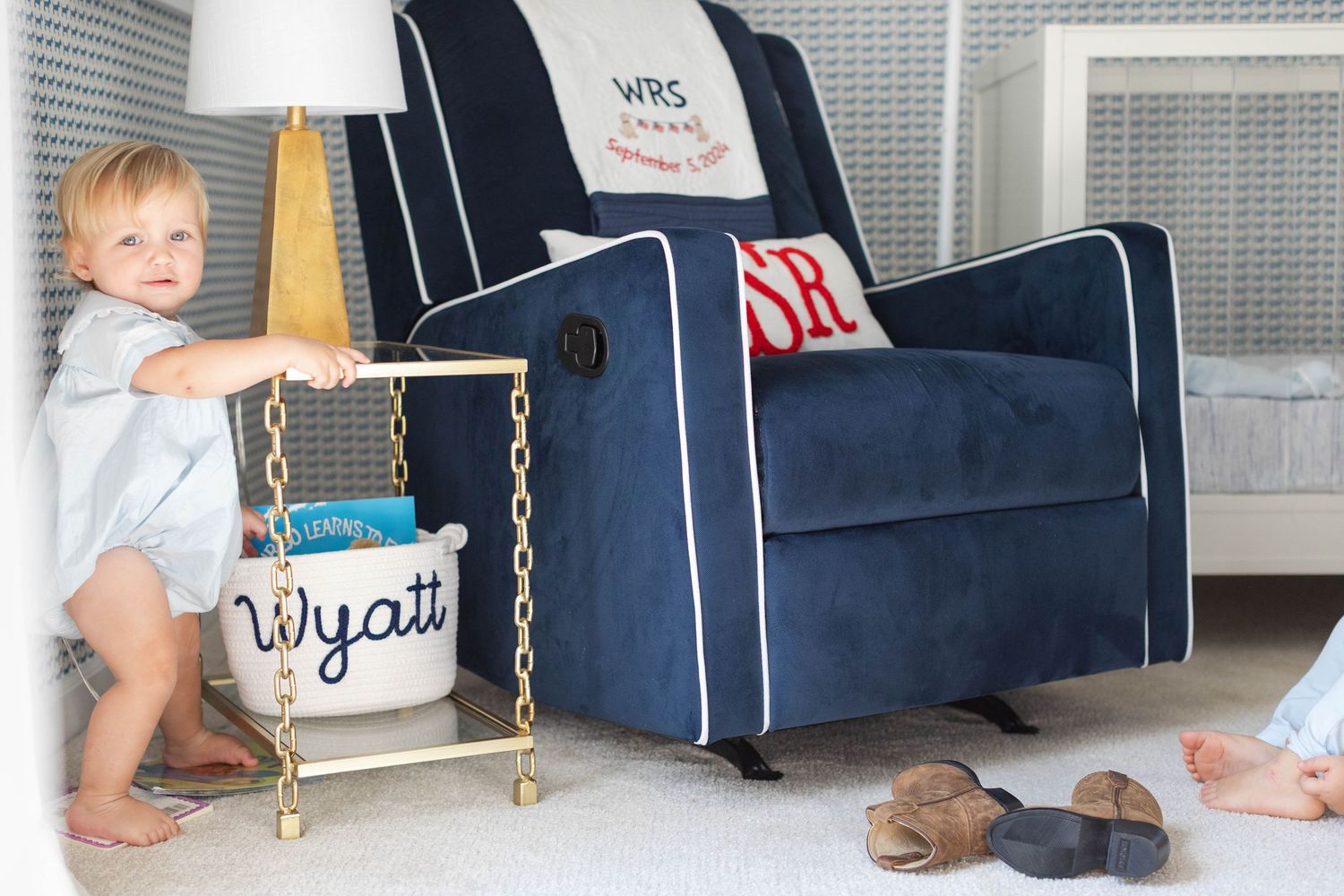 Navy and white striped backpacks line up neatly against a wall with gold chain straps and embroidered details.