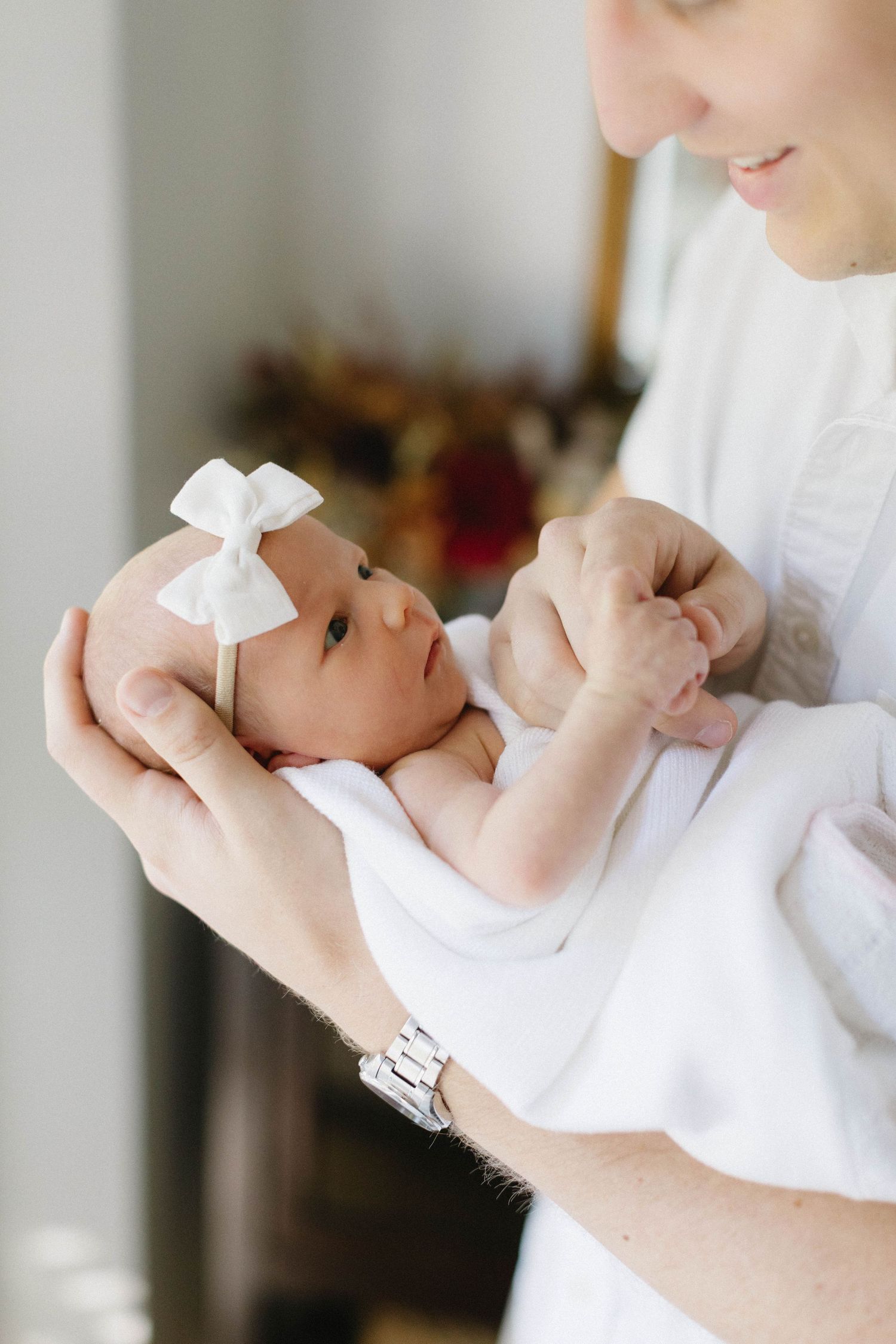 A caregiver cradles a white-clothed newborn baby while feeding, shown in a series of intimate bonding moments.