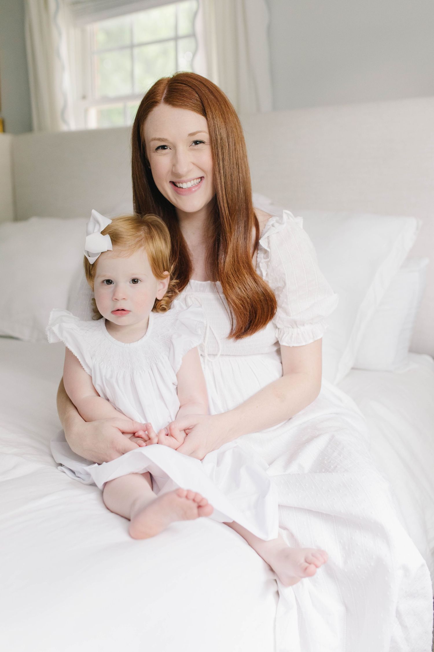Natural light newborn photo session on white bedding captures precious family bonding moments.
