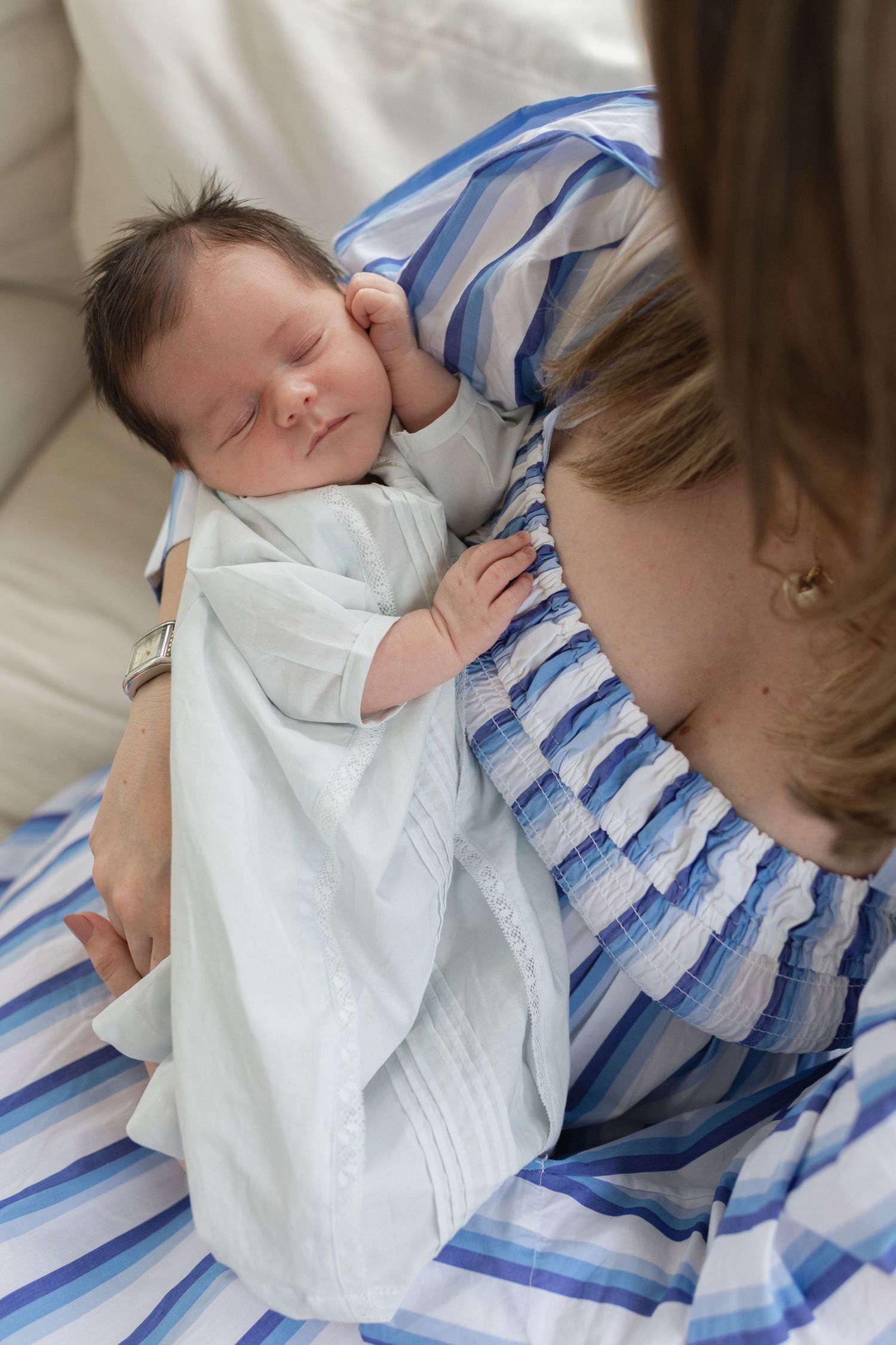 A series of intimate close-up shots showing a baby in white clothing being held.