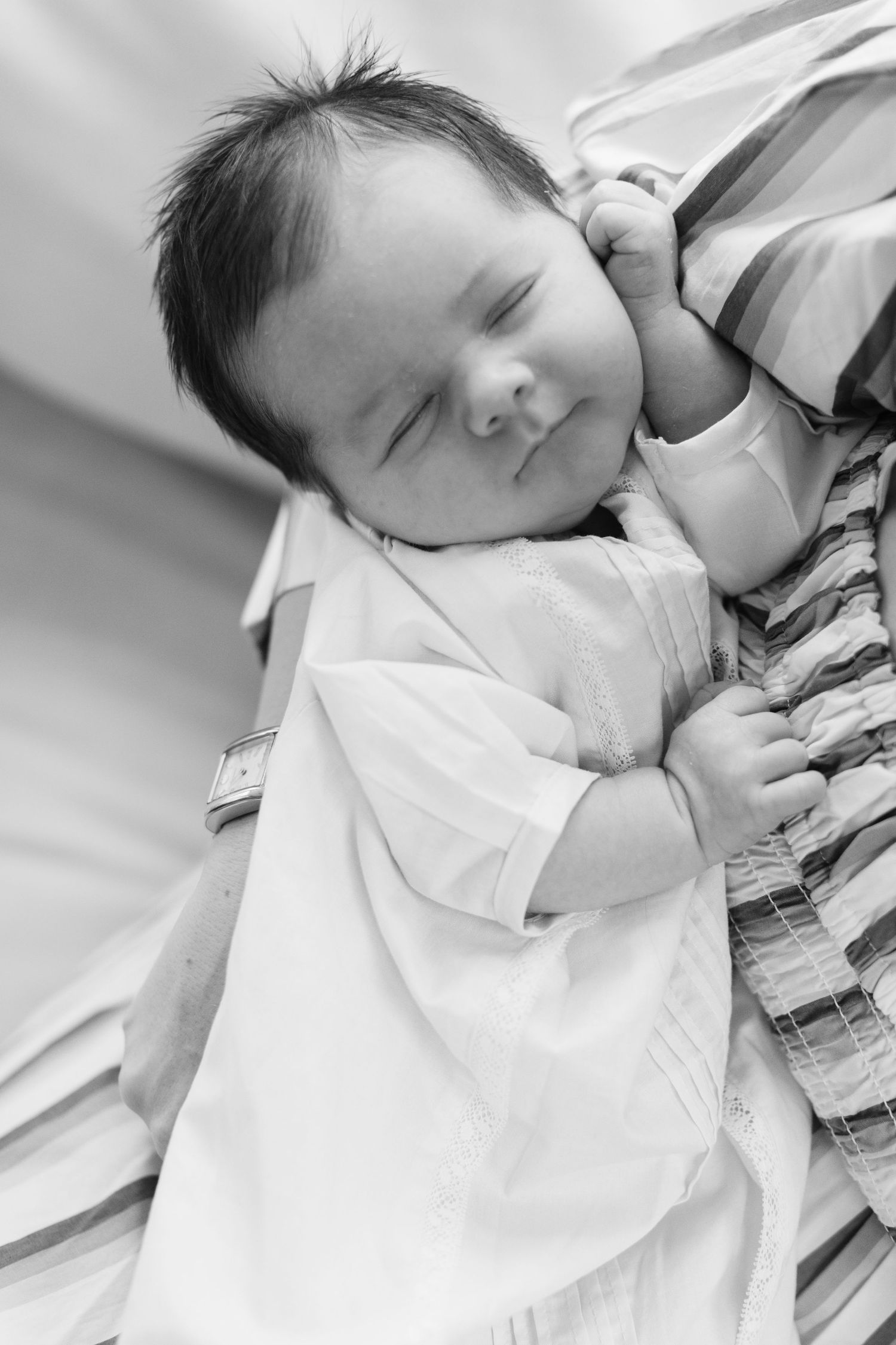 Close-up black and white series of a sleeping newborn in white clothing.
