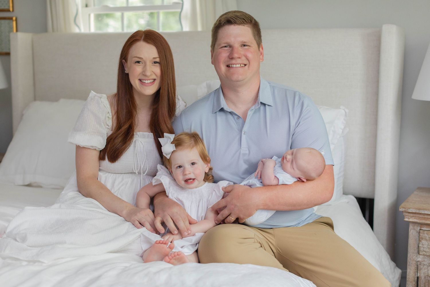 Family of four poses together in soft neutral colors during indoor photoshoot.