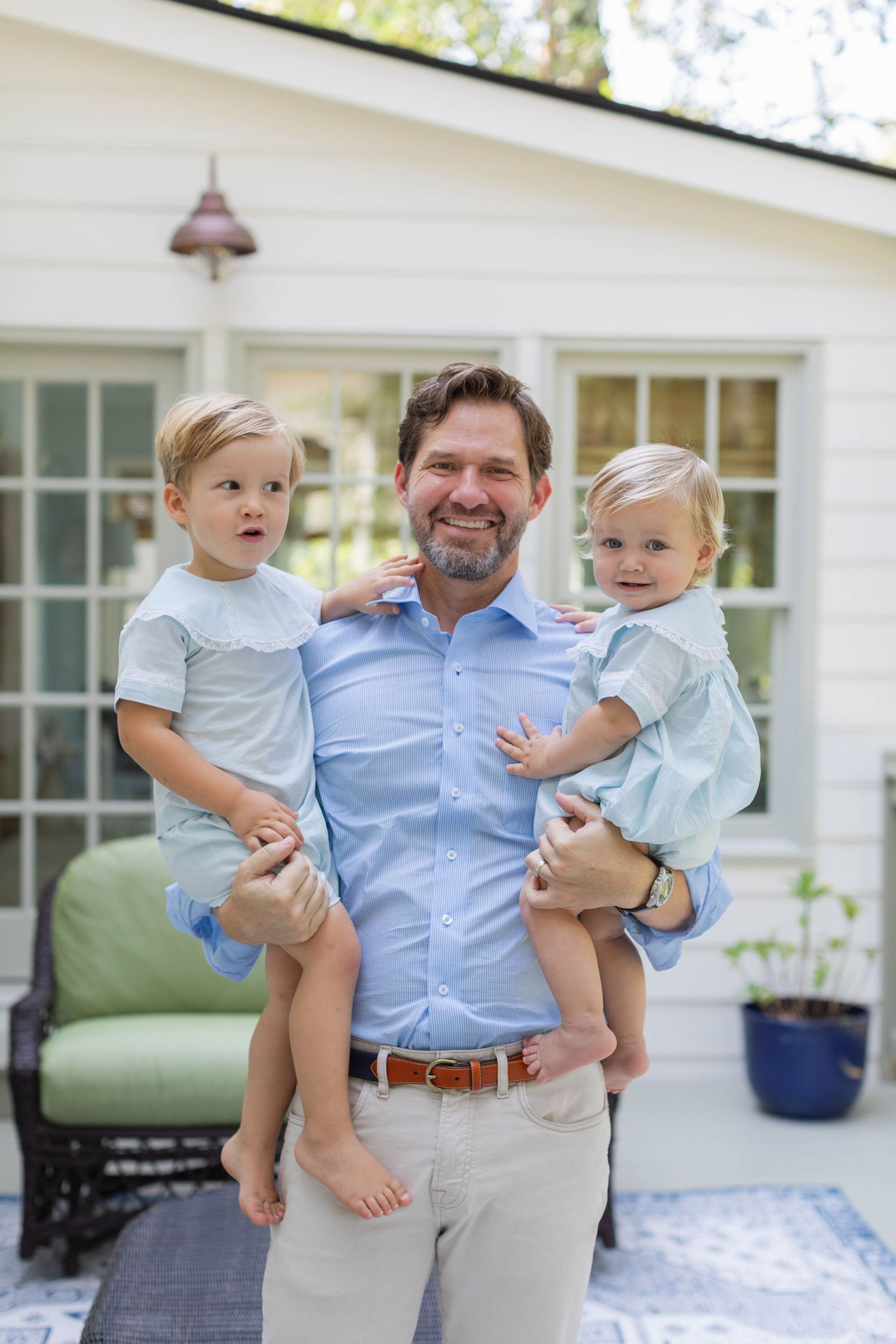 Candid family photos on a white porch show joyful interactions between adult and two toddlers in coordinated blue outfits.