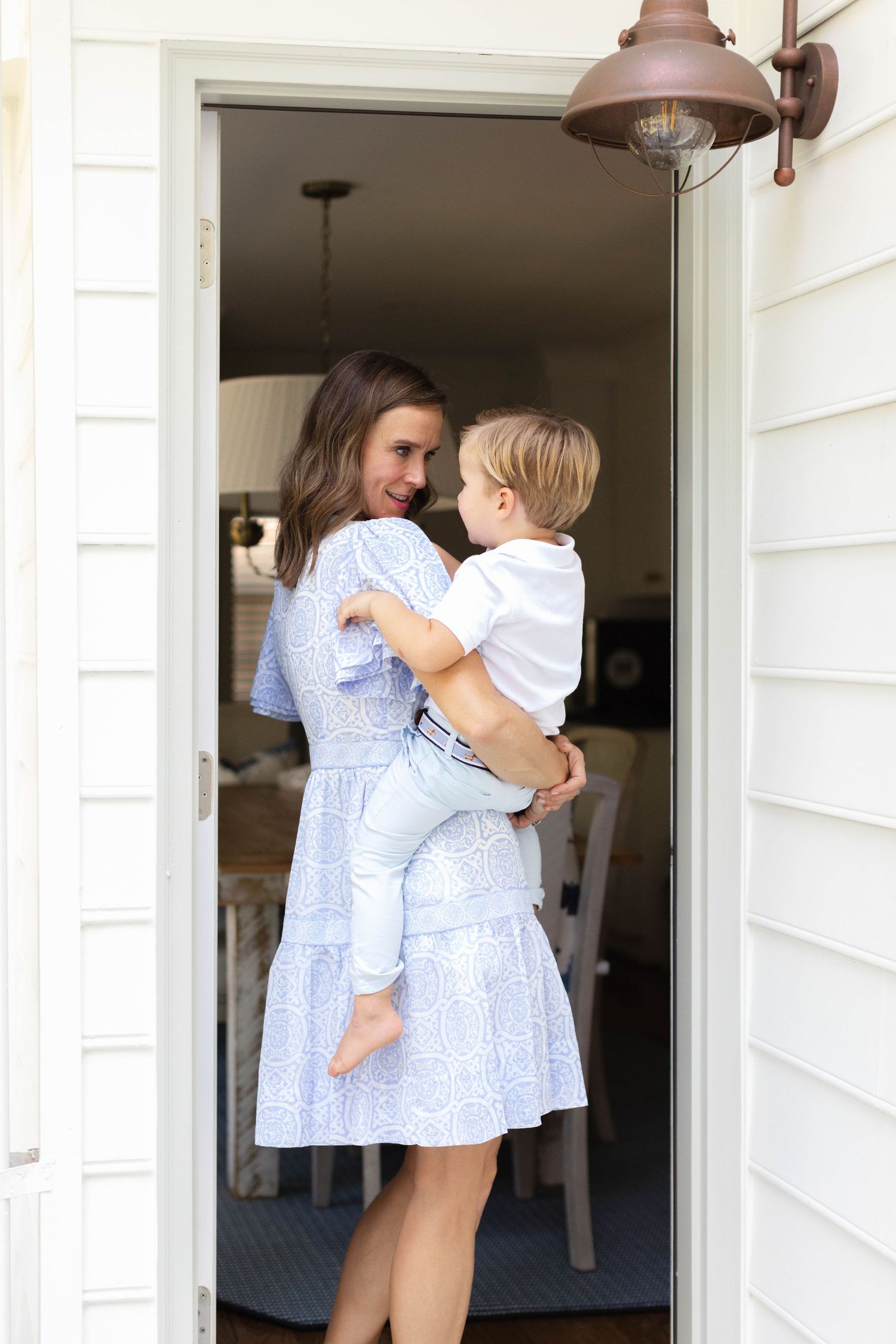 An intimate family moment captured in a doorway wearing matching blue and white dresses.