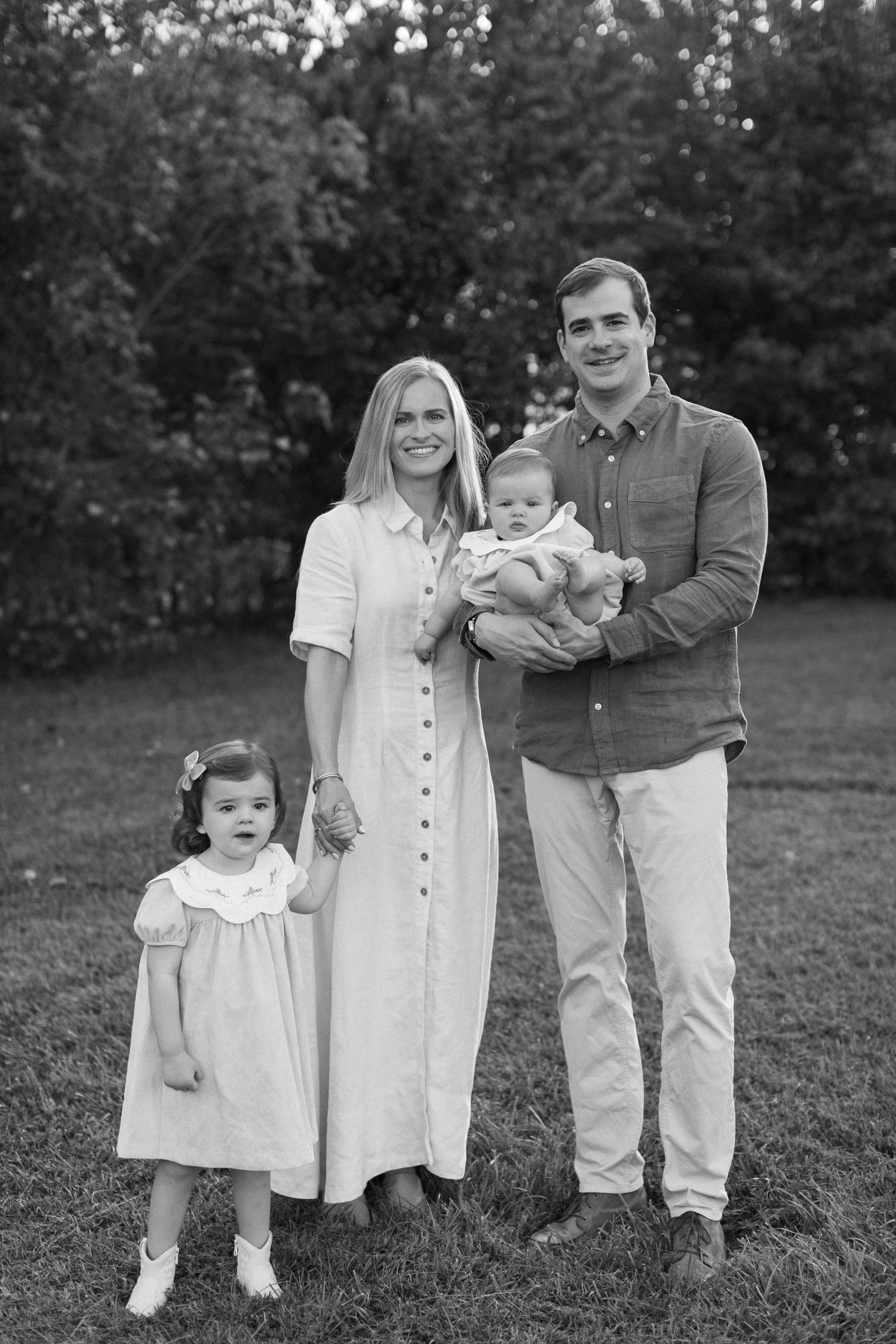 A black and white photo series showing a young family outdoors in coordinating white and khaki casual outfits.