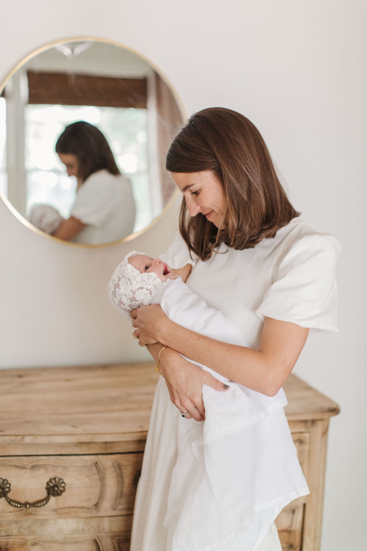 Tender moments with newborn against rustic wooden dresser.