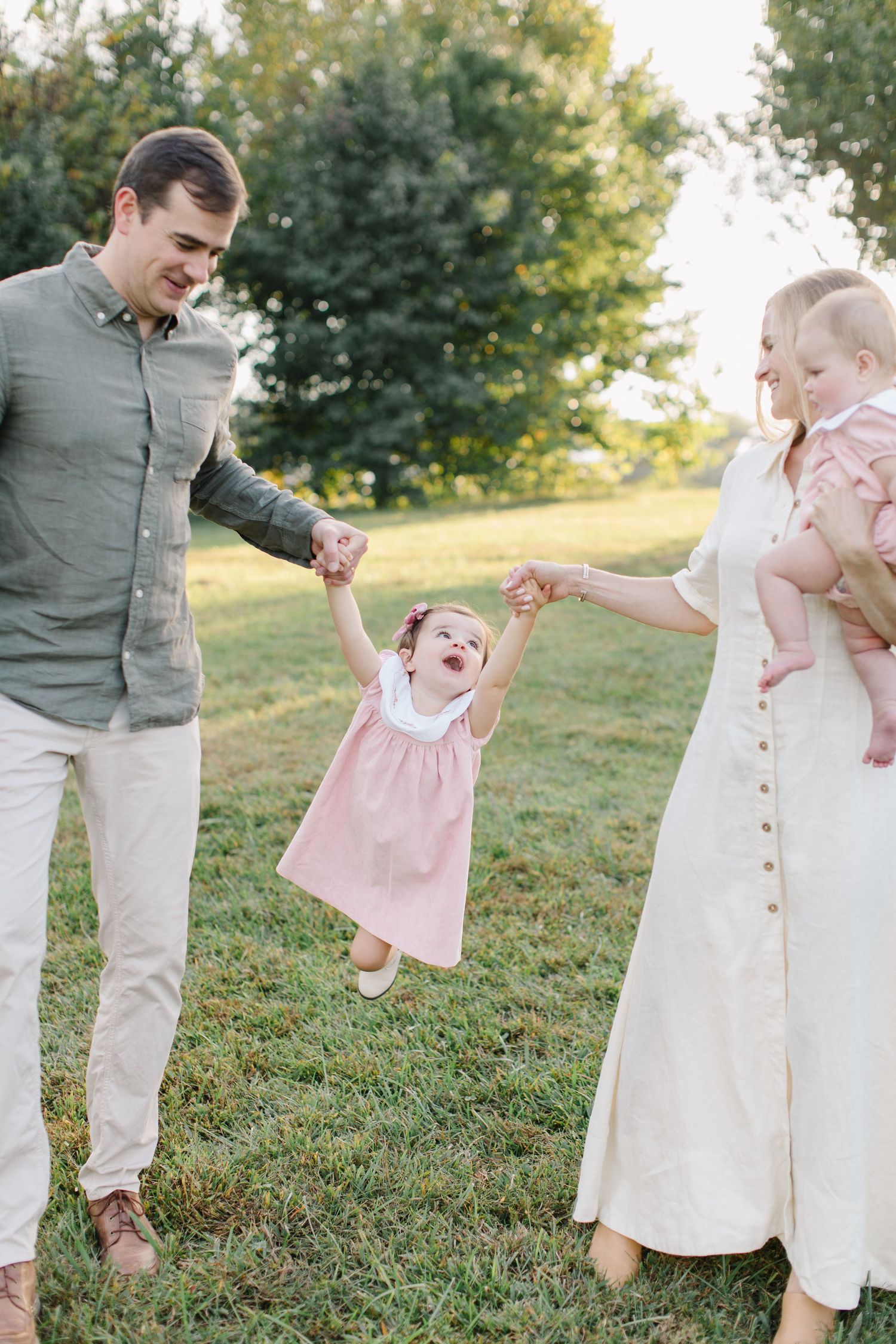 A series of playful outdoor family photos showing joyful moments between adults and children in coordinated pink and white outfits.