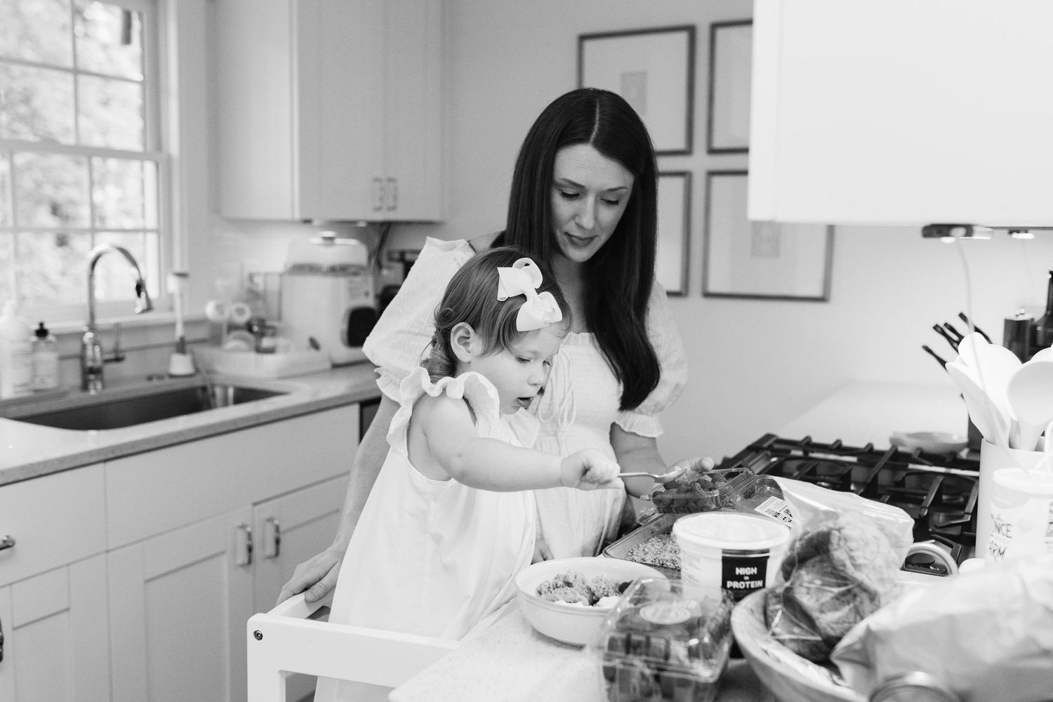 Black and white candid kitchen scene shows quiet moments of daily family life.