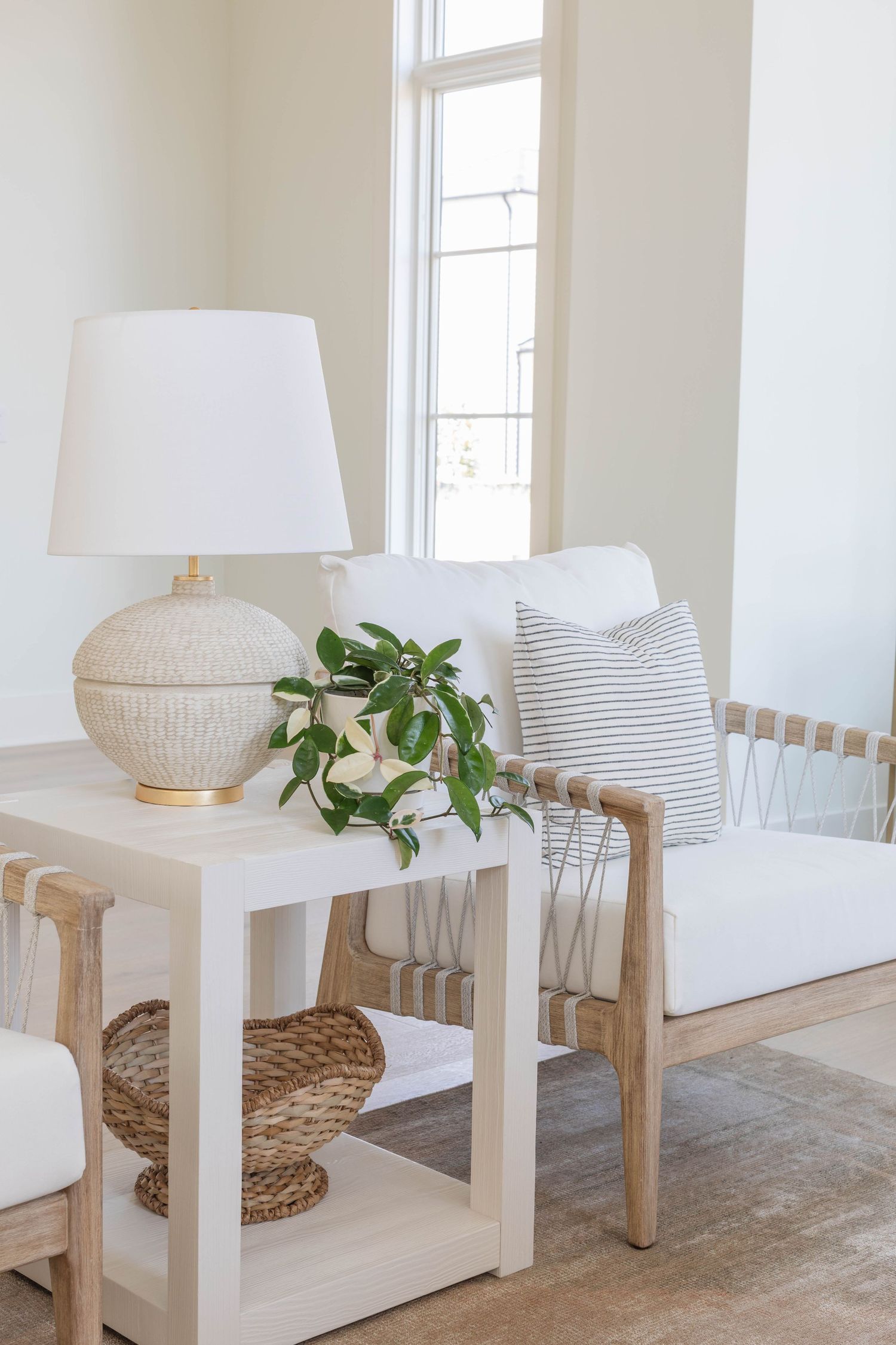 Minimalist living room interior with white chairs, woven poufs, and decorative plants - Atlanta Interior Design Photography
