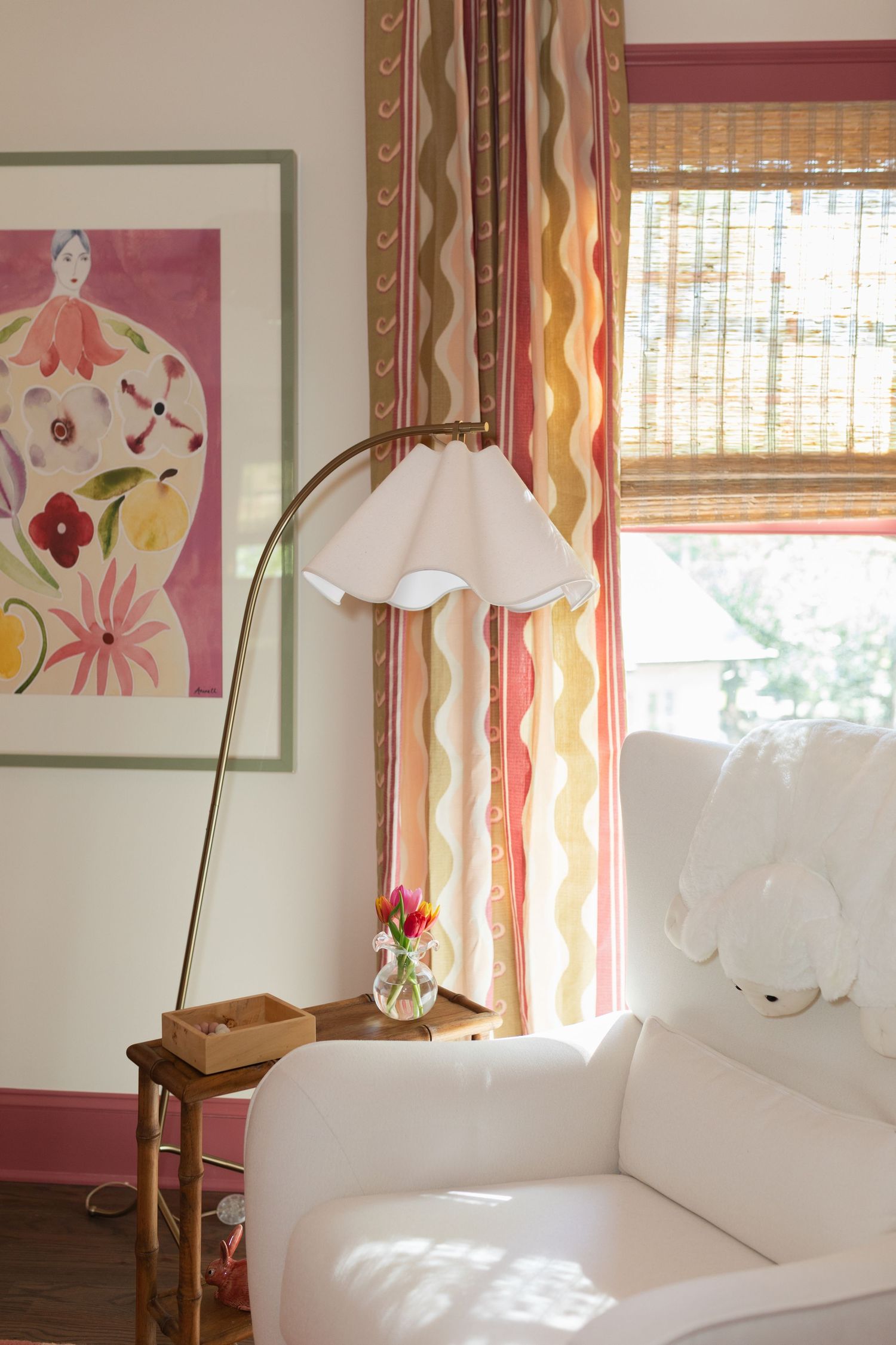 Cozy nursery corner with white arc floor lamp, striped curtains, floral wall art, and white sofa chair.