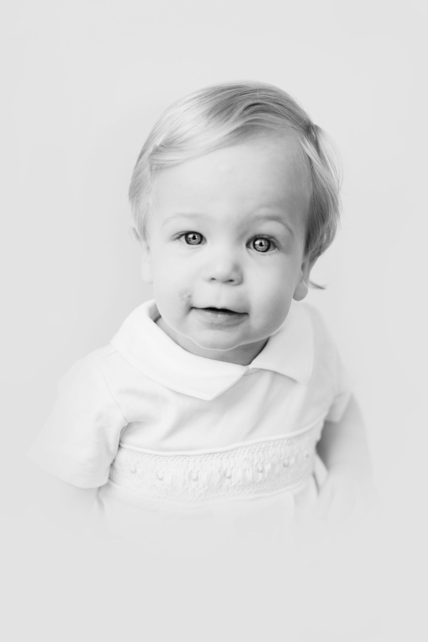 High key black and white portrait series of a baby with bright eyes and sweet expressions against white background.