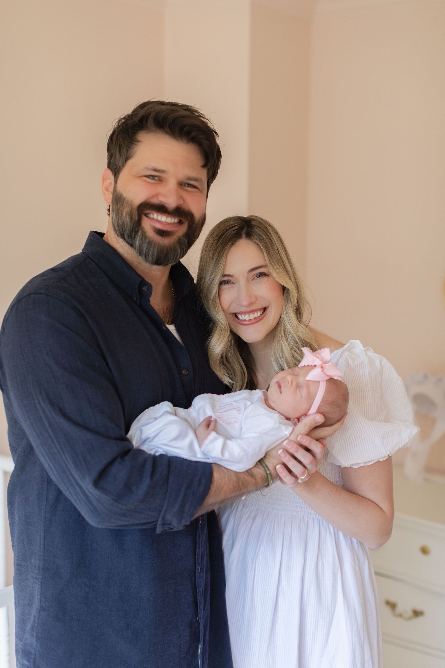 A family of three shares a joyful moment together in their nursery room.