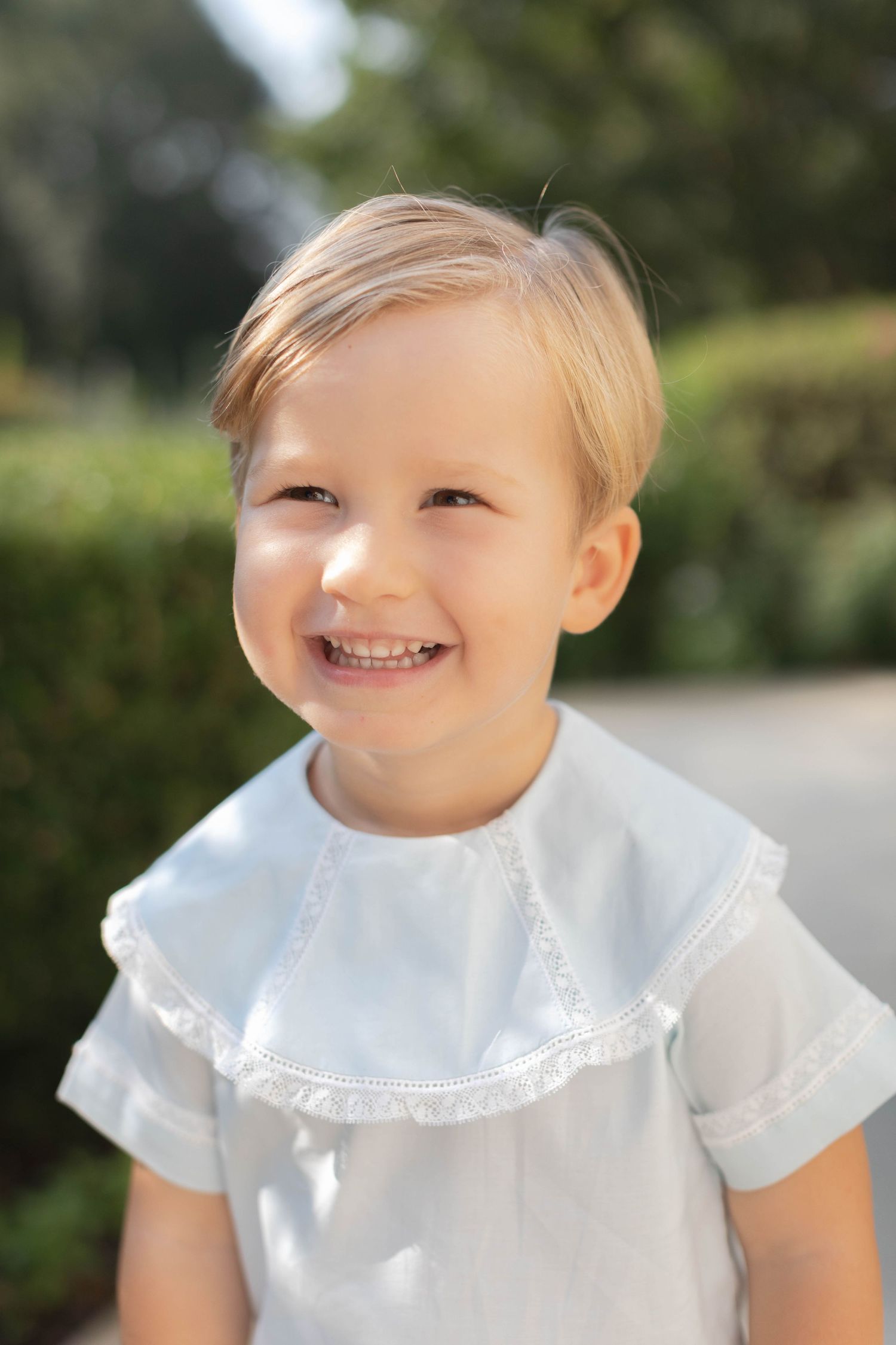 A series of four connected photos showing a child wearing a white lace-collared shirt in an outdoor setting.